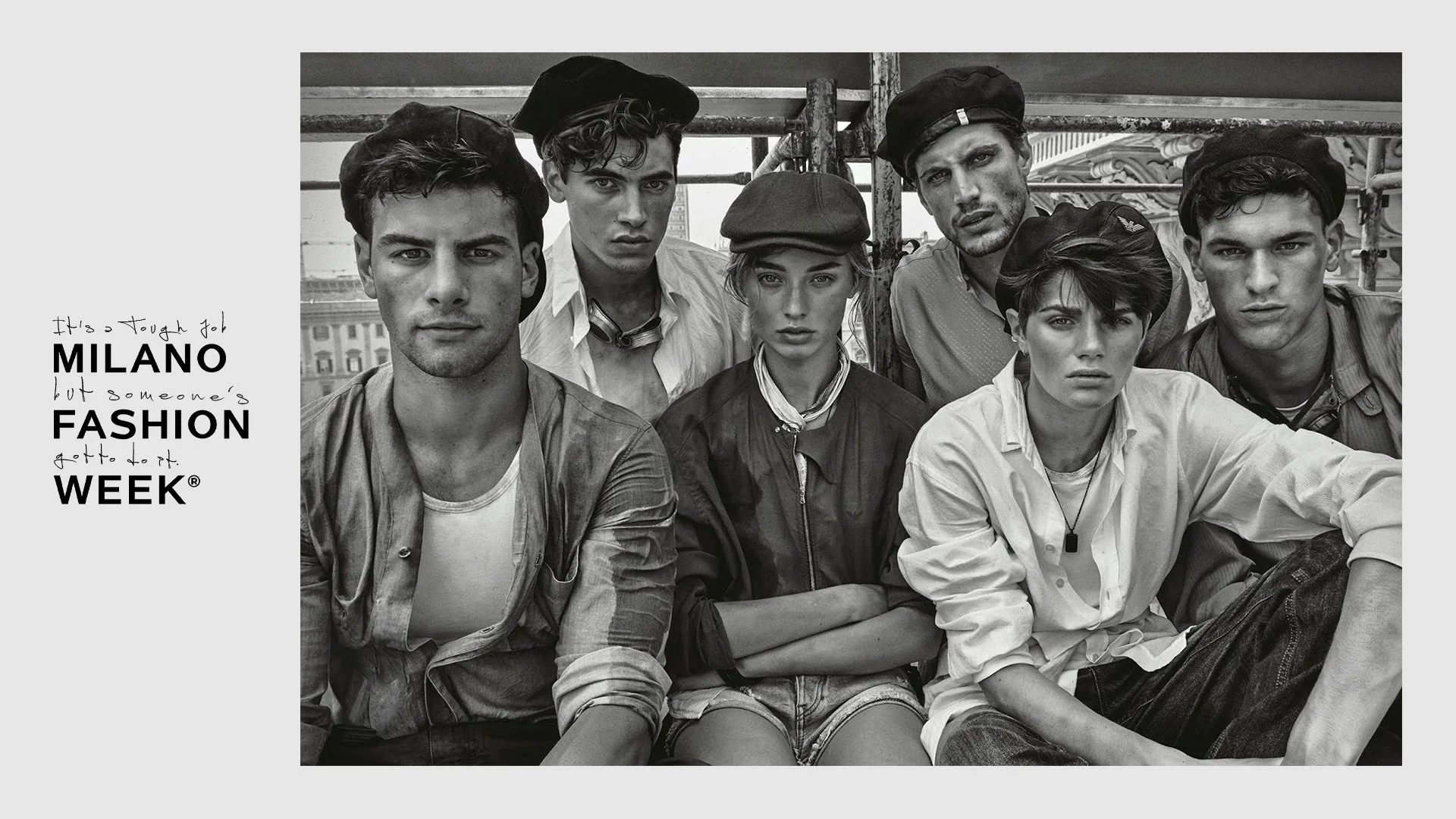 Una fotografia in bianco e nero di un gruppo di giovani persone, uomini e donne, con espressioni serie, indossando abbigliamento casual e cappelli, seduti o in piedi in un ambiente urbano.