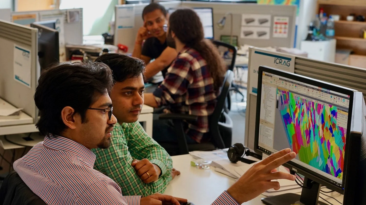  Two scientists examine geological research on screen