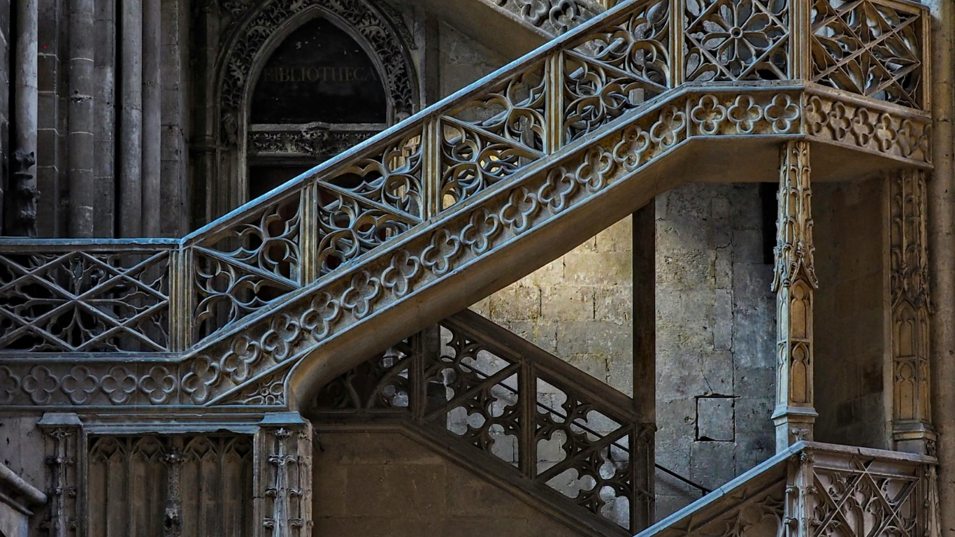 Escalier en pierre à motifs gothiques dans une ancienne bâtisse.