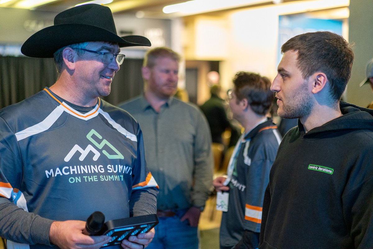 manufacturing community. Two men in conversation at manufacturing conference or event Machining Summit On The Summit