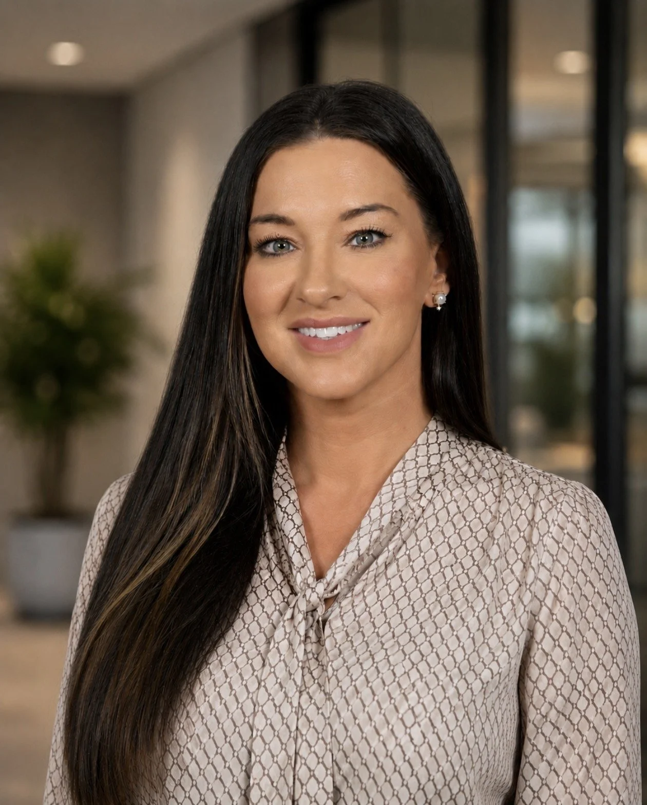 Professional woman with long dark hair smiling in an office setting.