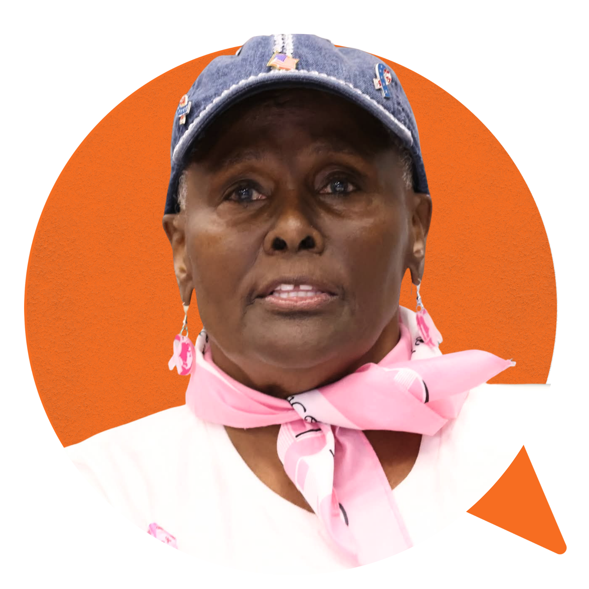 Close-up of an older African American woman wearing a denim cap with patriotic pins, a pink bandana with hearts, and earrings, with an orange and white background.