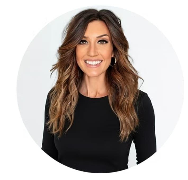 Portrait of a smiling woman with wavy brown hair wearing a black top against a white background.