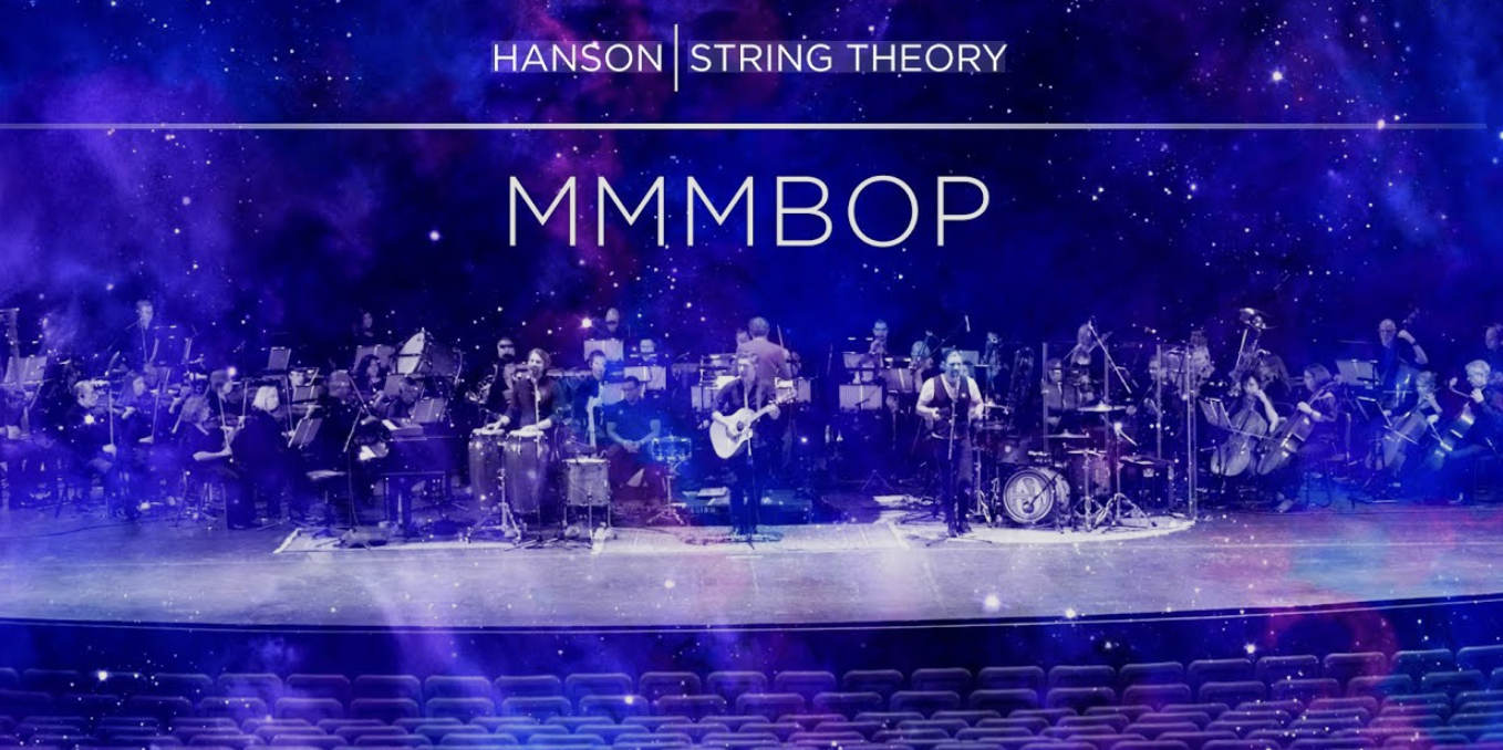 An orchestra performing on stage with a backdrop that reads 'Hanson String Theory' and 'MMM BOP' in purple and blue galaxy-themed design.