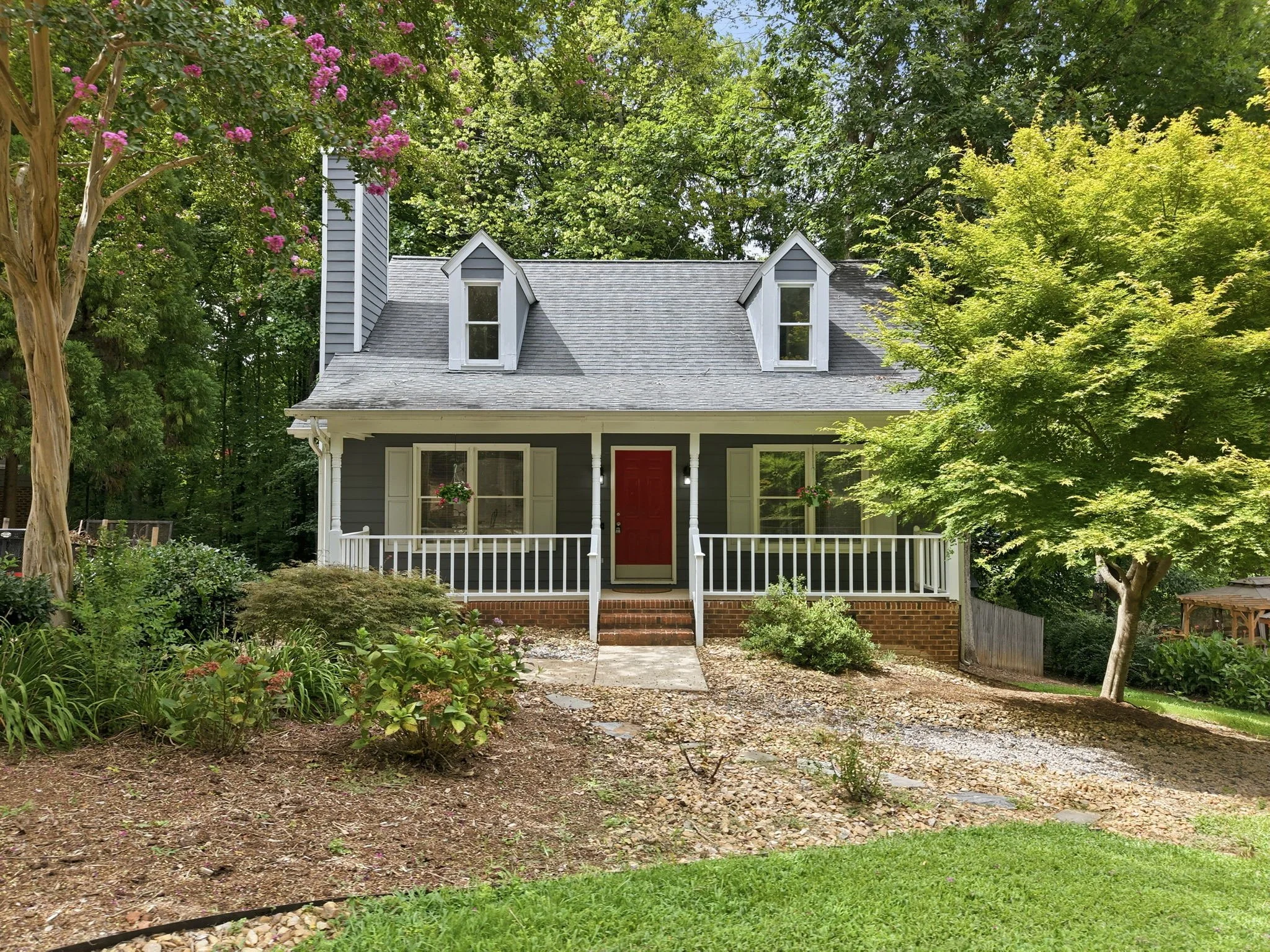 Charming Cary home with a front porch, mature trees, and lush landscaping
