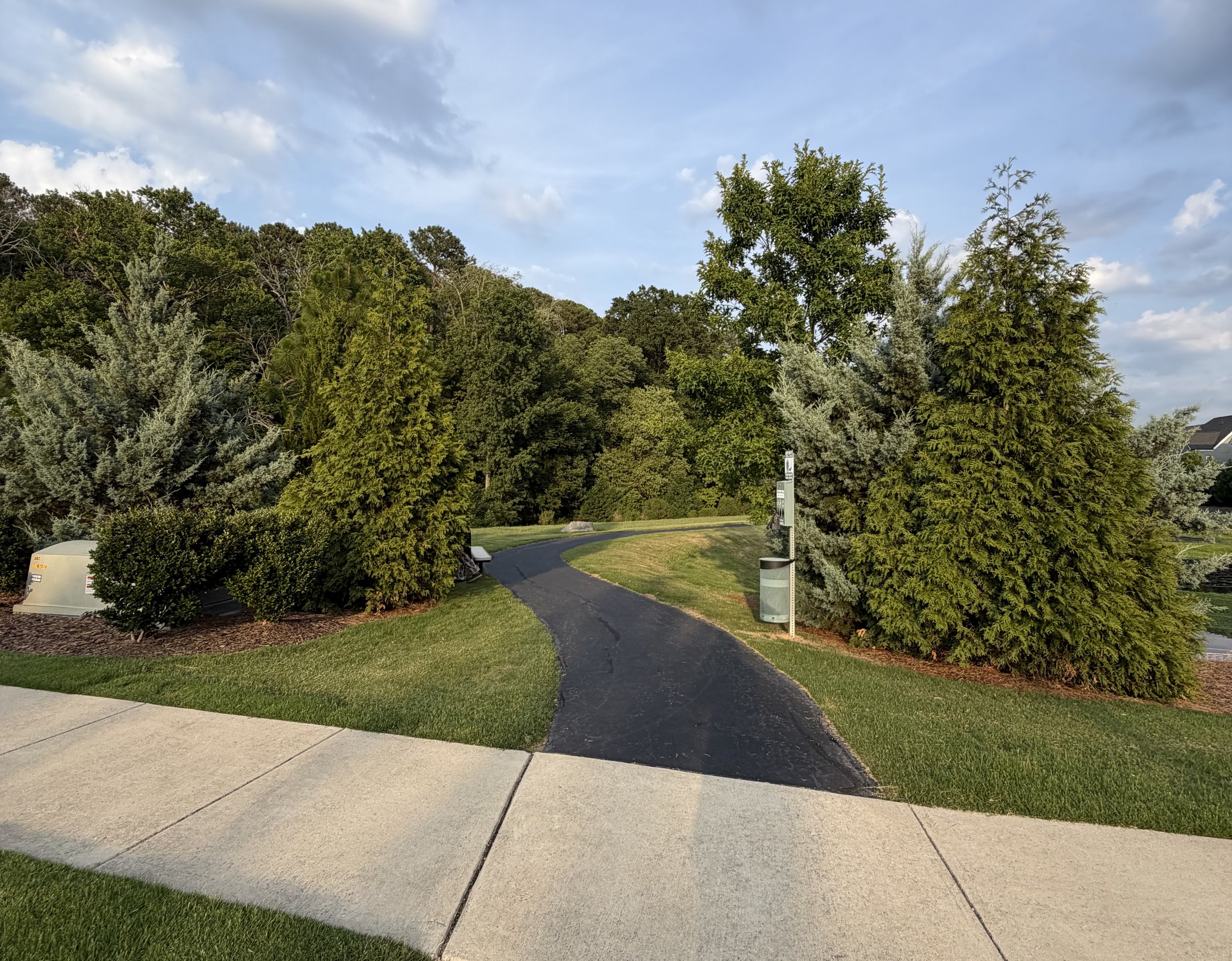 Paved walking path surrounded by mature trees and landscaped greenery in a Cary, North Carolina community.