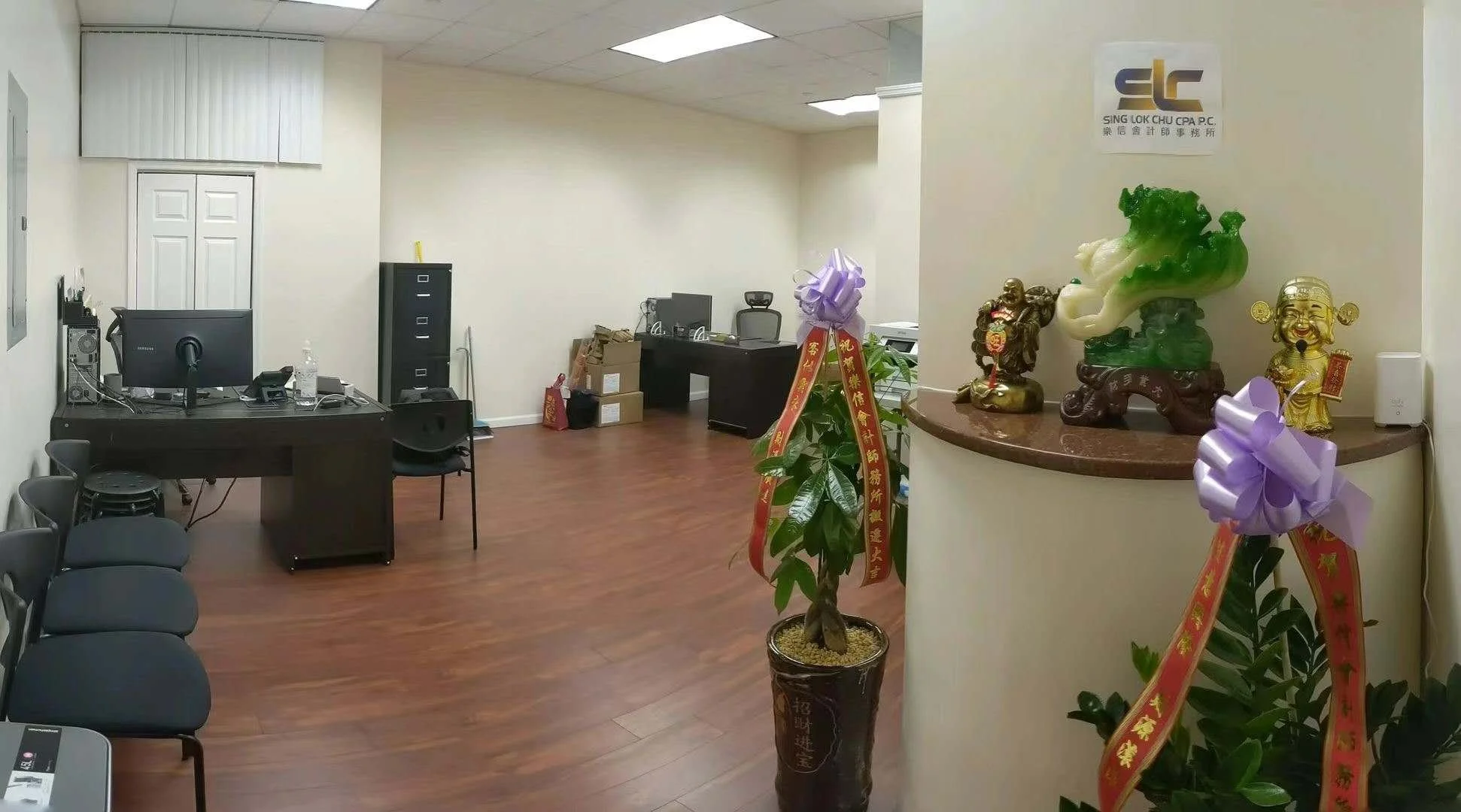An office room with a desk, computer, and chairs, decorated with Chinese ornaments and plants.