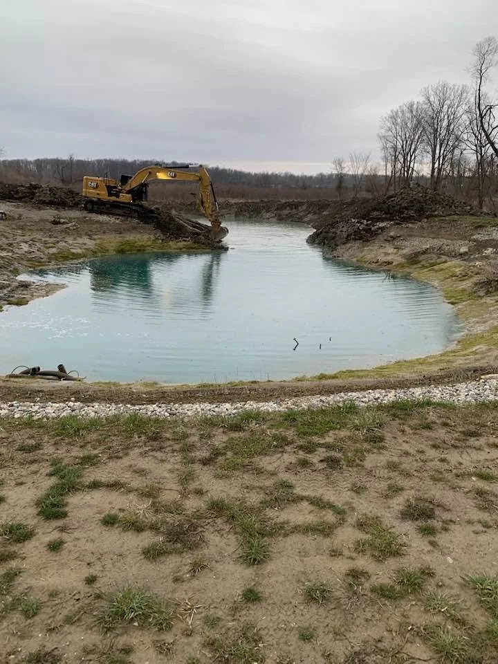 excavator digging new pond in rural area.