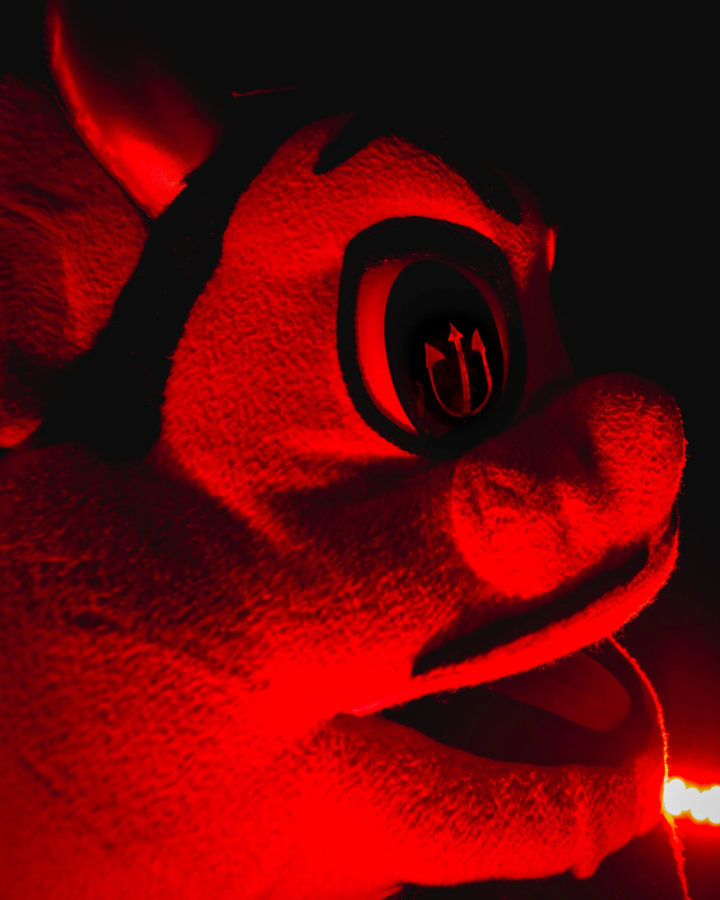 Close-up of a rolled red towel with a black stripe, illuminated by red light, showing the texture of the fabric and the edge of the towel.