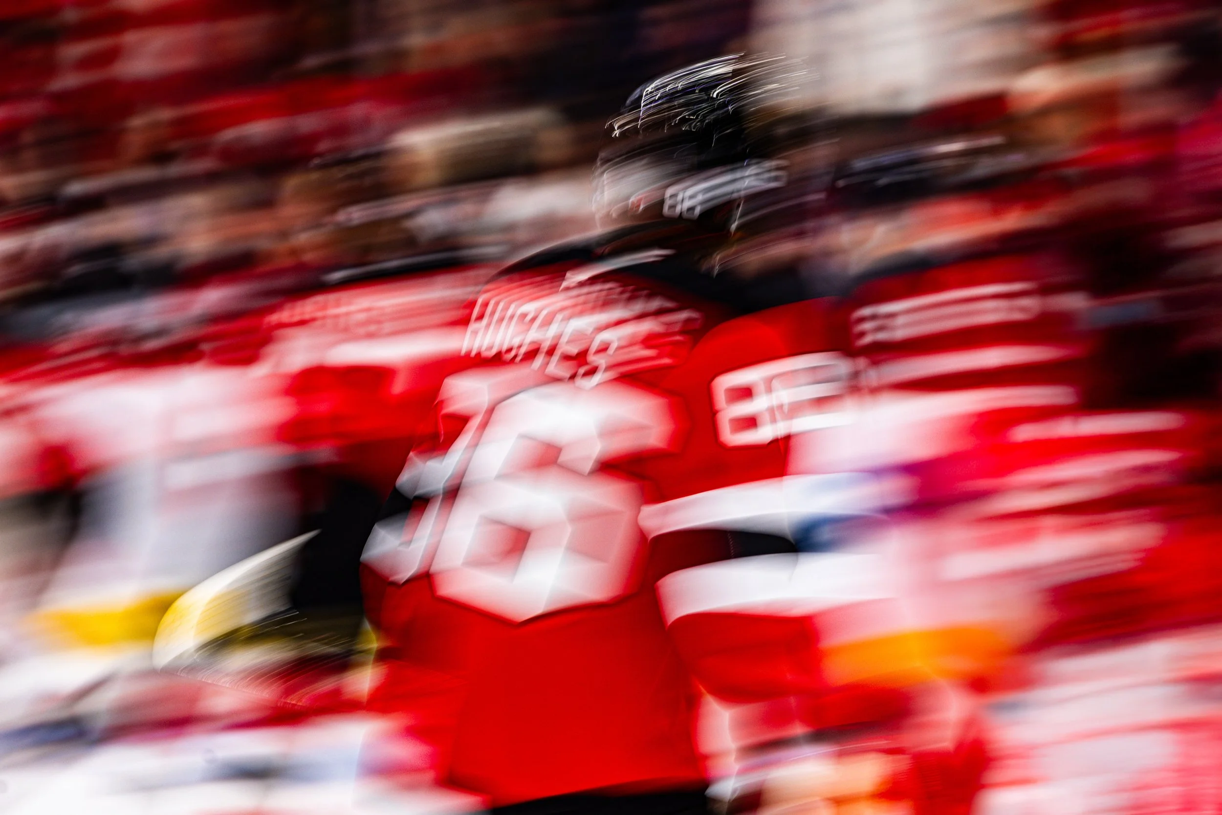 A blurred image of a person wearing a red sports uniform with white and black details, likely in a sports stadium or arena.