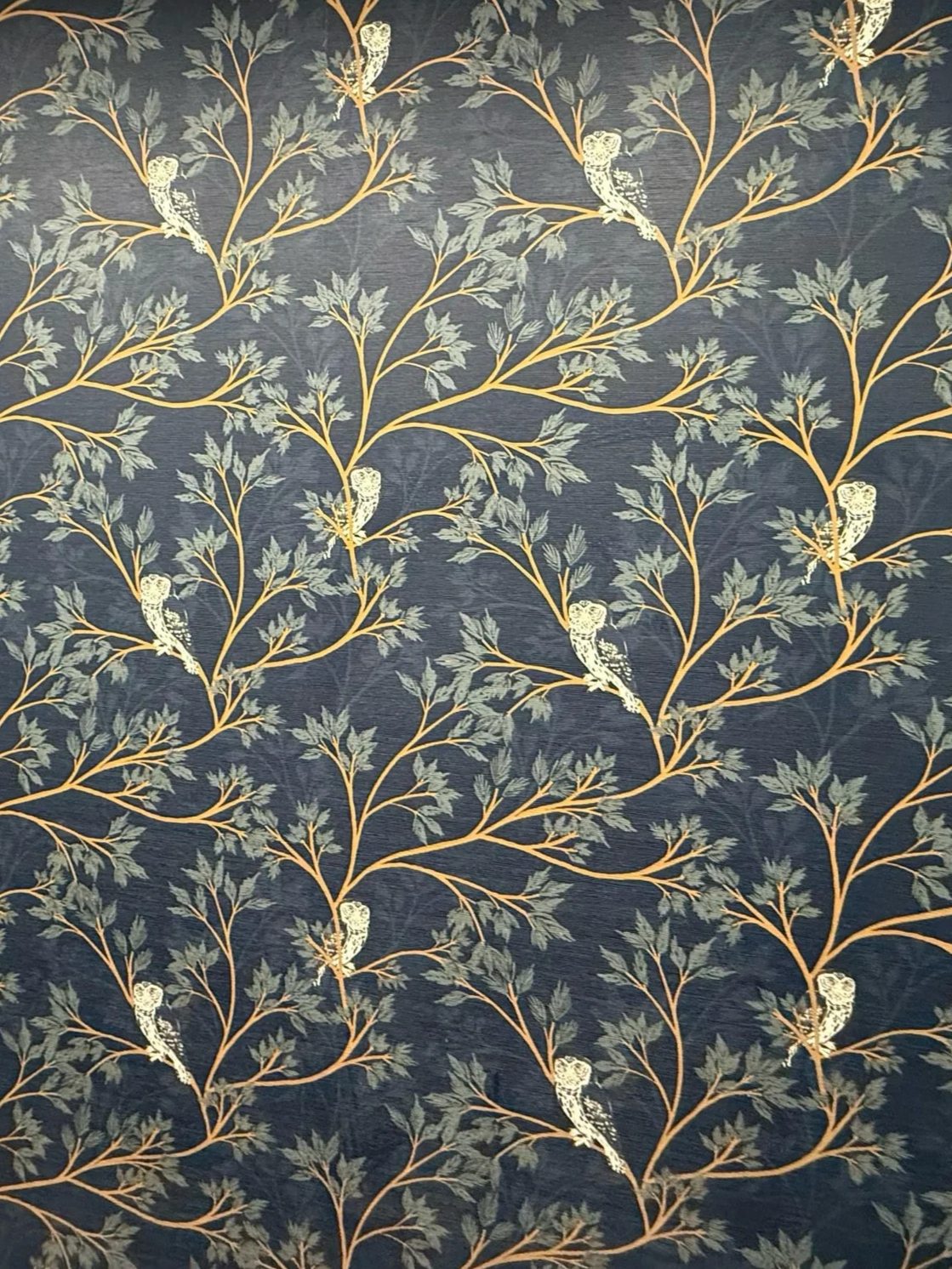 Decorative fabric with a pattern of trees, leaves, and white birds on a dark background.