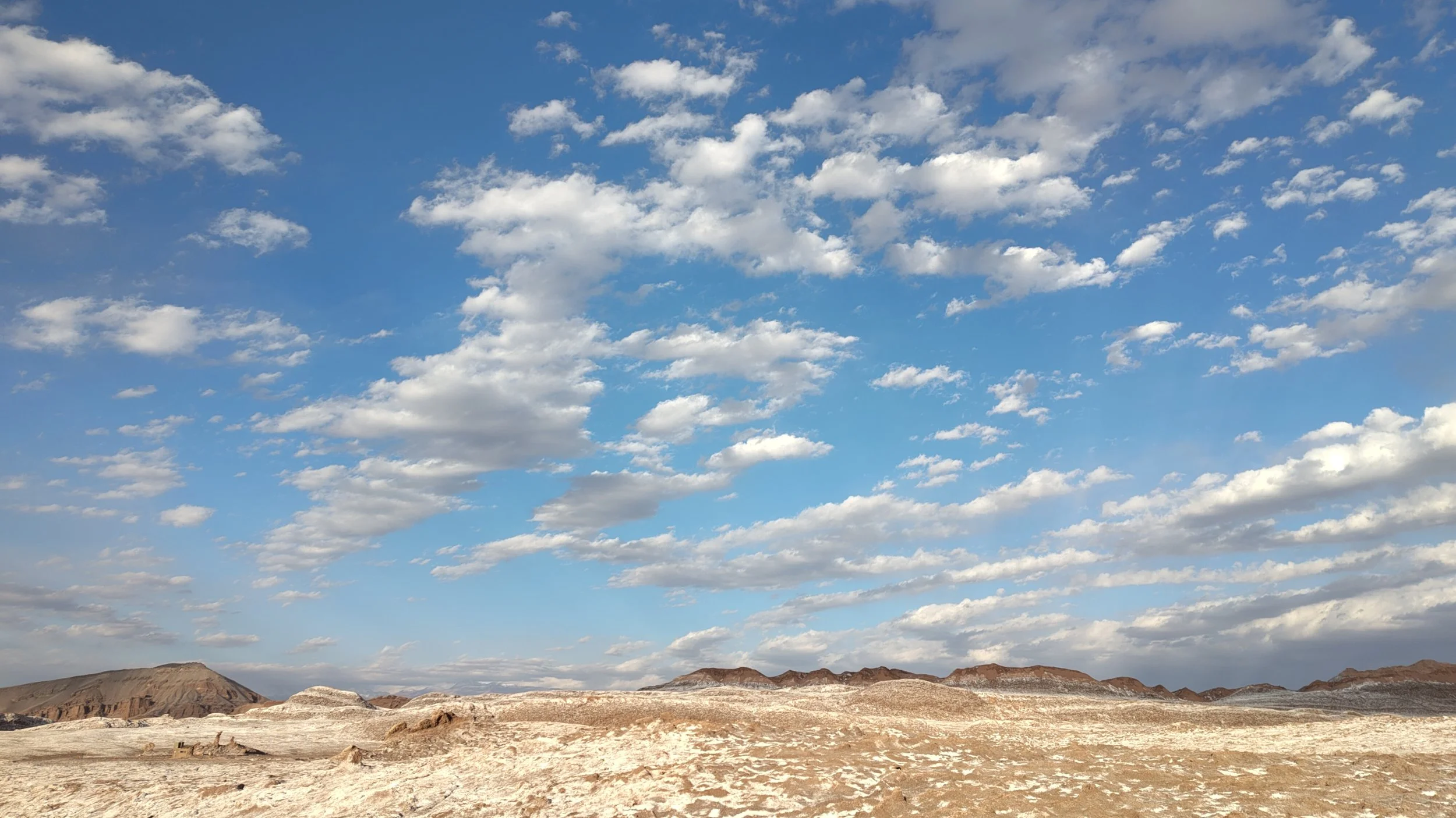 Blick auf eine trockene, felsige Landschaft unter einem blauen Himmel mit vereinzelten Wolken.