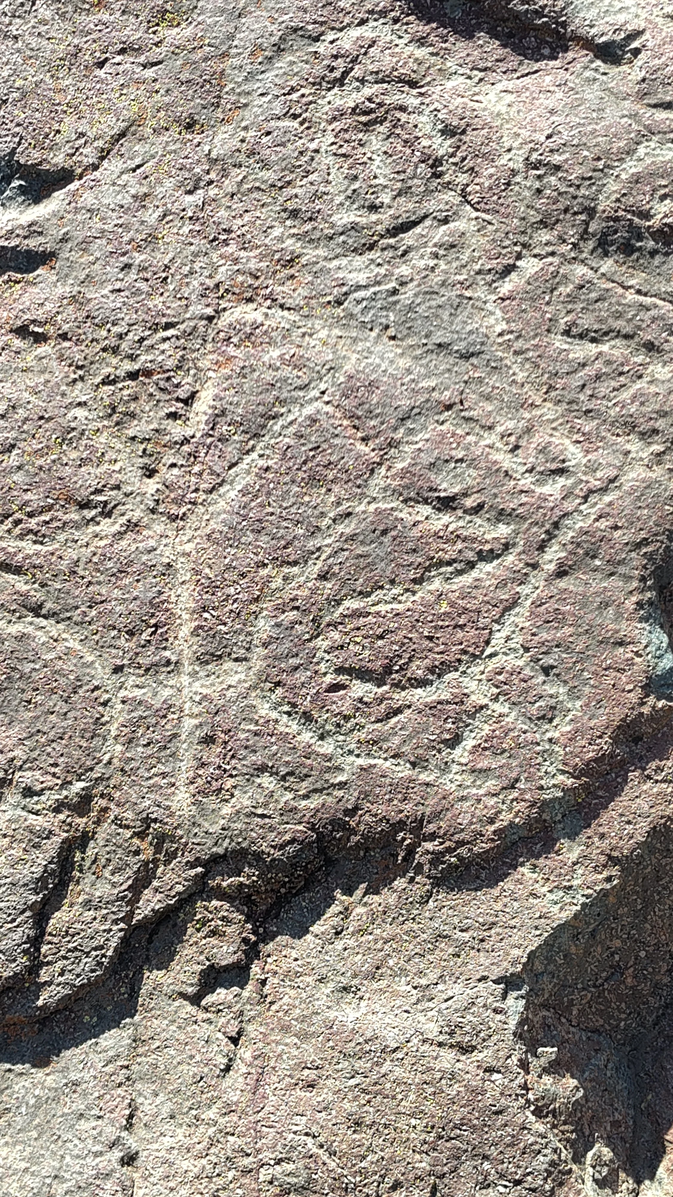 Roter, grobkörniger Felsen mit natürlichen Rillen und Oberflächenstrukturen.