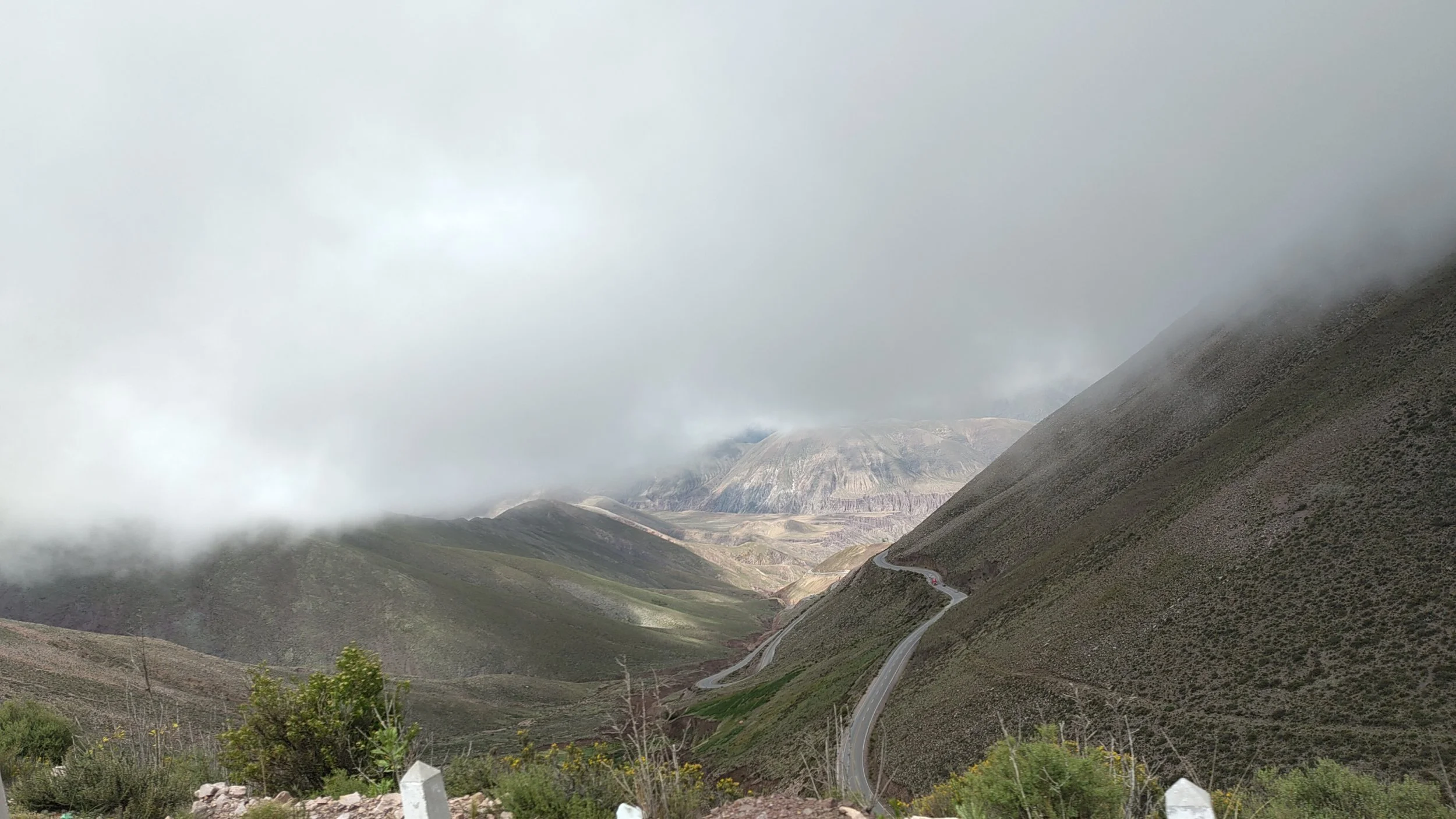 Hügelige Berge mit einer kurvigen Straße, Wolken und Nebel