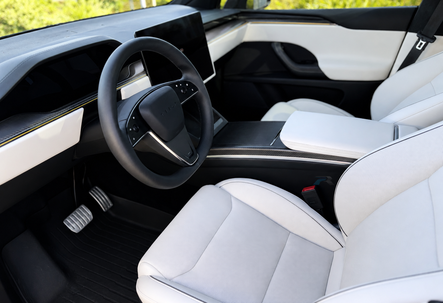 Interior of a Tesla electric vehicle, showing a sleek black steering wheel, digital dashboard, white seats, and modern dashboard design.