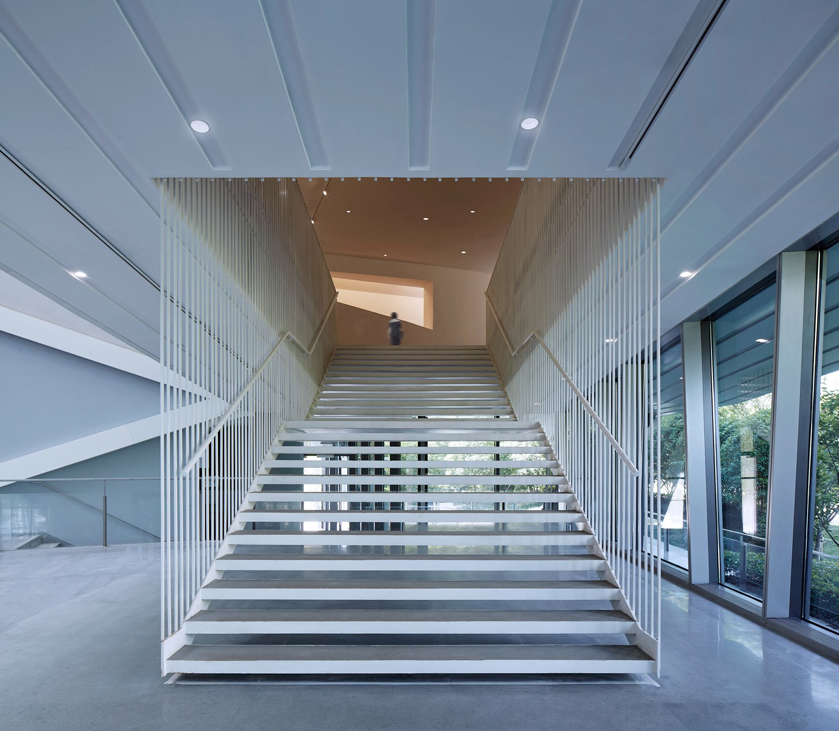 Escalera moderna en un edificio de vidrio con paredes de ventanas y diseño minimalista.