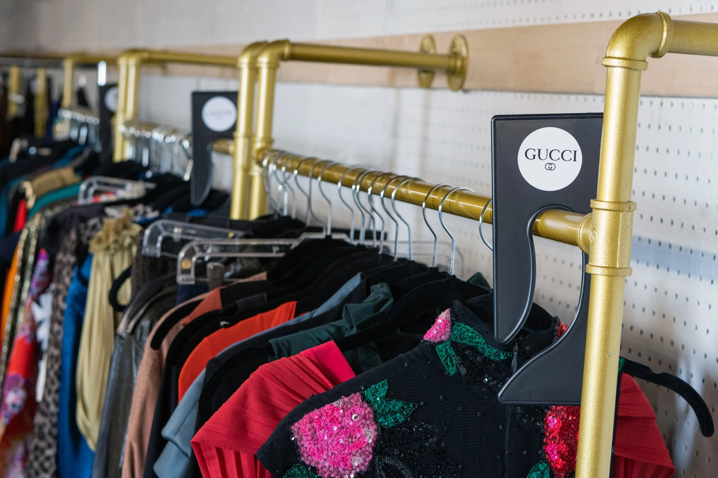 Clothing racks with colorful dresses and shirts, with Gucci store tags visible.