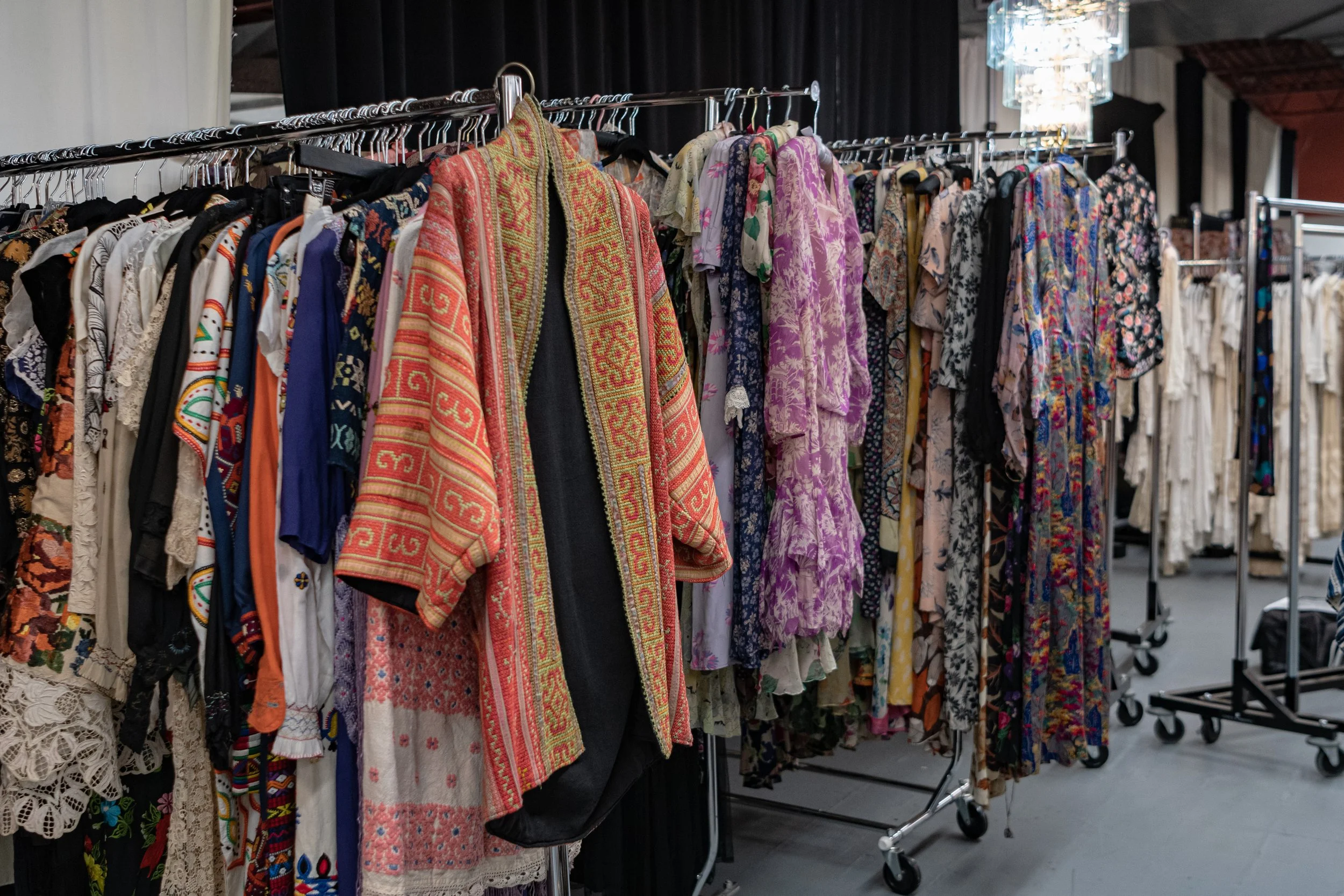 Clothing rack filled with colorful dresses and garments at a thrift store or clothing sale event.