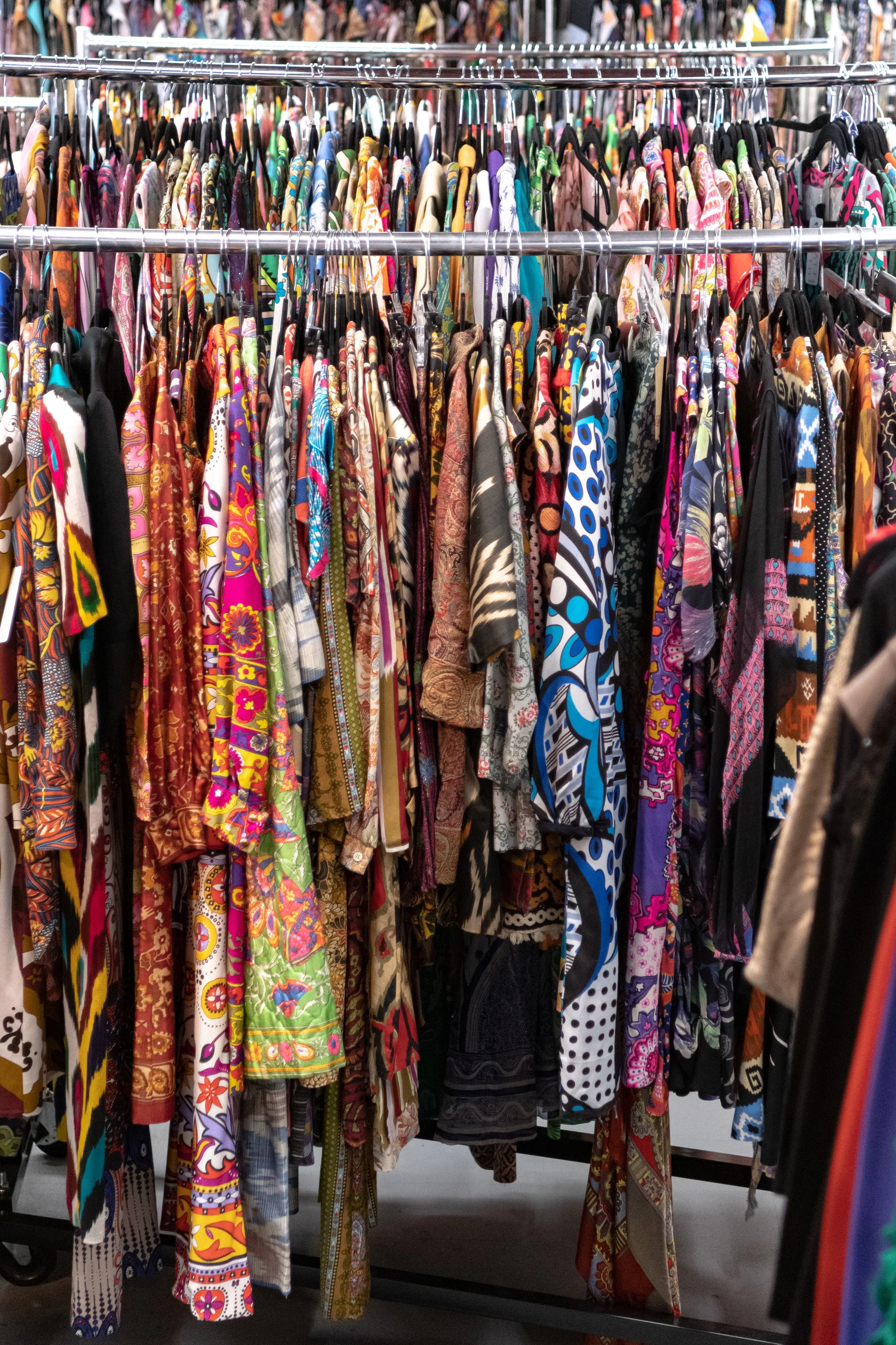 Clothing store display with racks of colorful, patterned shirts on hangers.