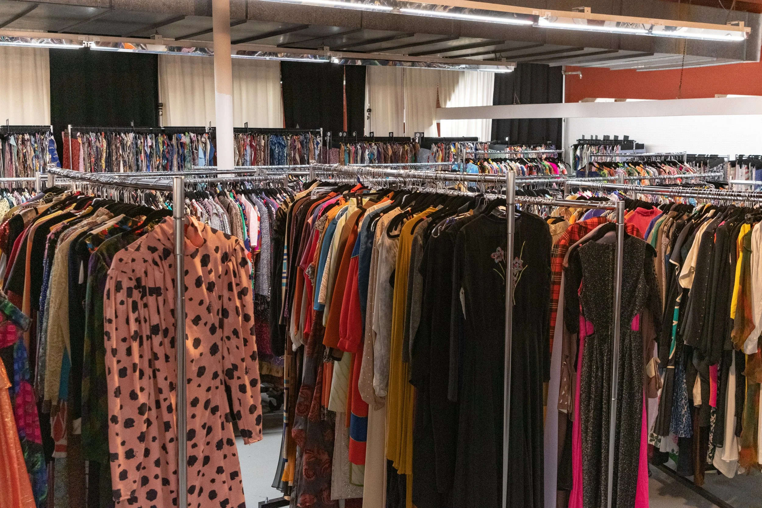 Clothing racks filled with various colorful garments in a thrift store or boutique.