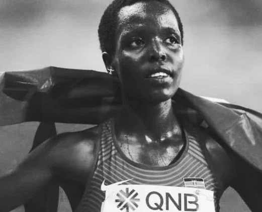 An African-American female athlete carrying a bag over her shoulder, wearing a sports tank top, after a race or workout.