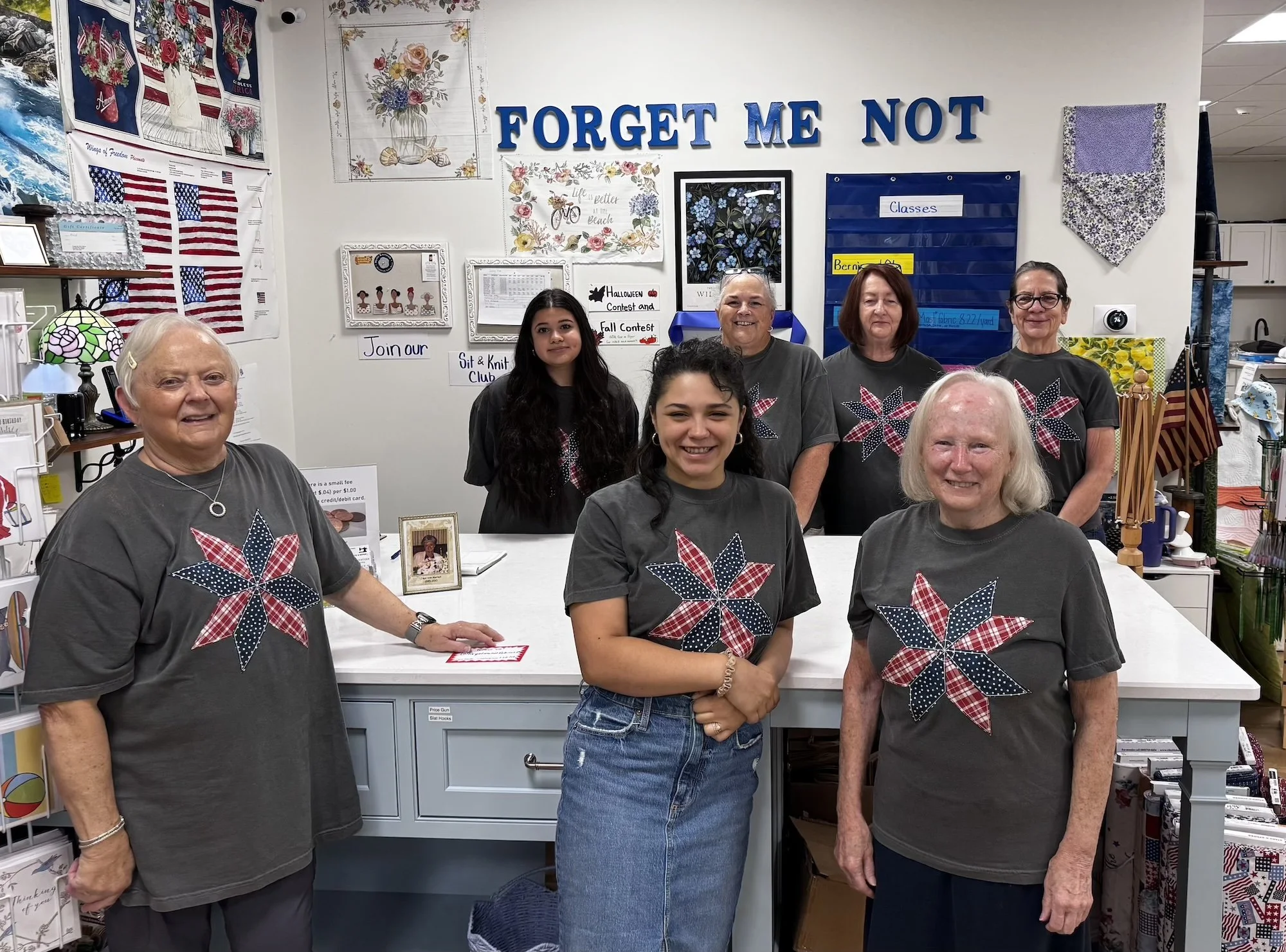 7 women standing around a counter all wearing staff shirts