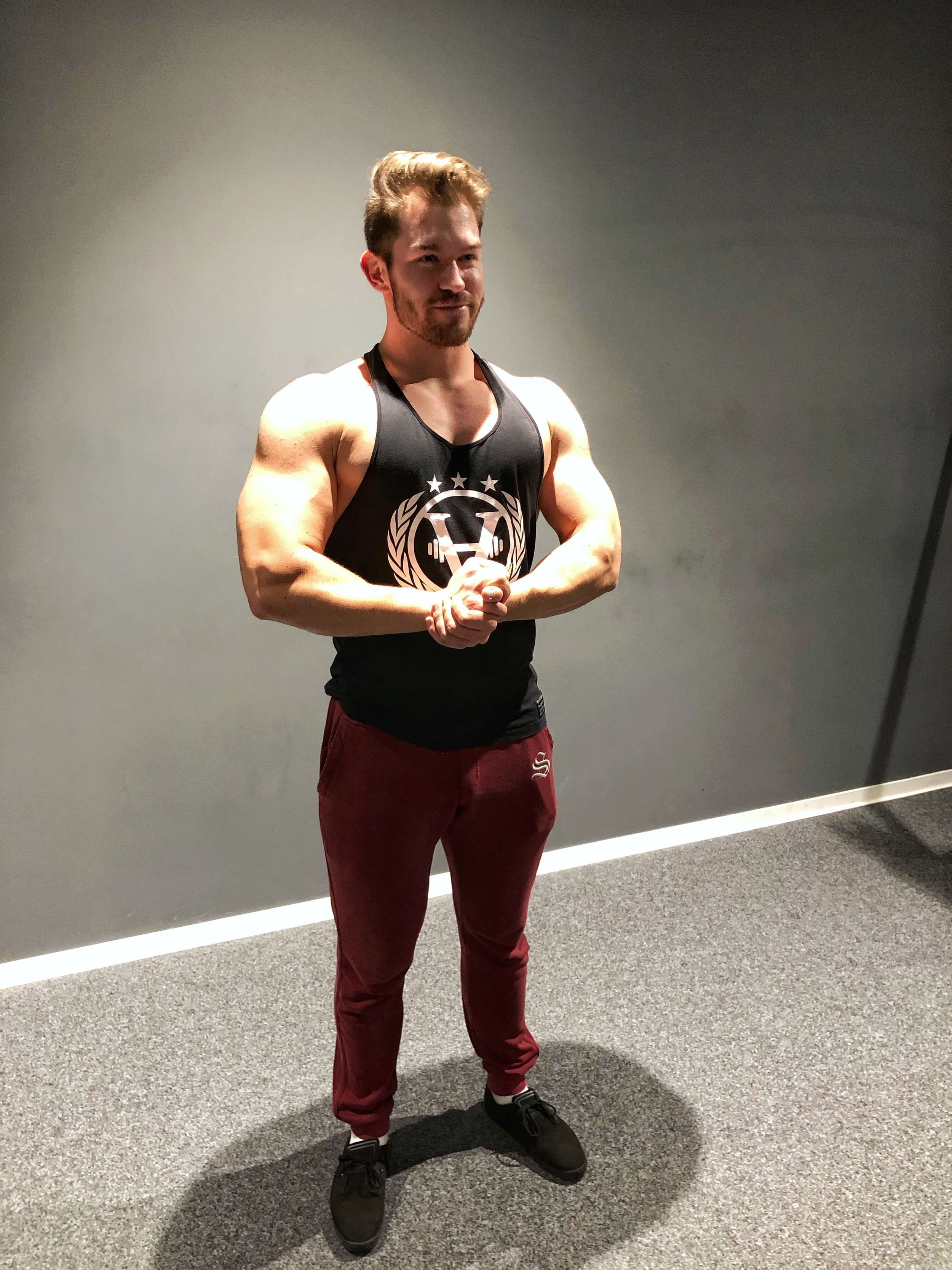 Toni Rämisch steht im Fitnessstudio und zeigt seinen trainierten Oberkörper