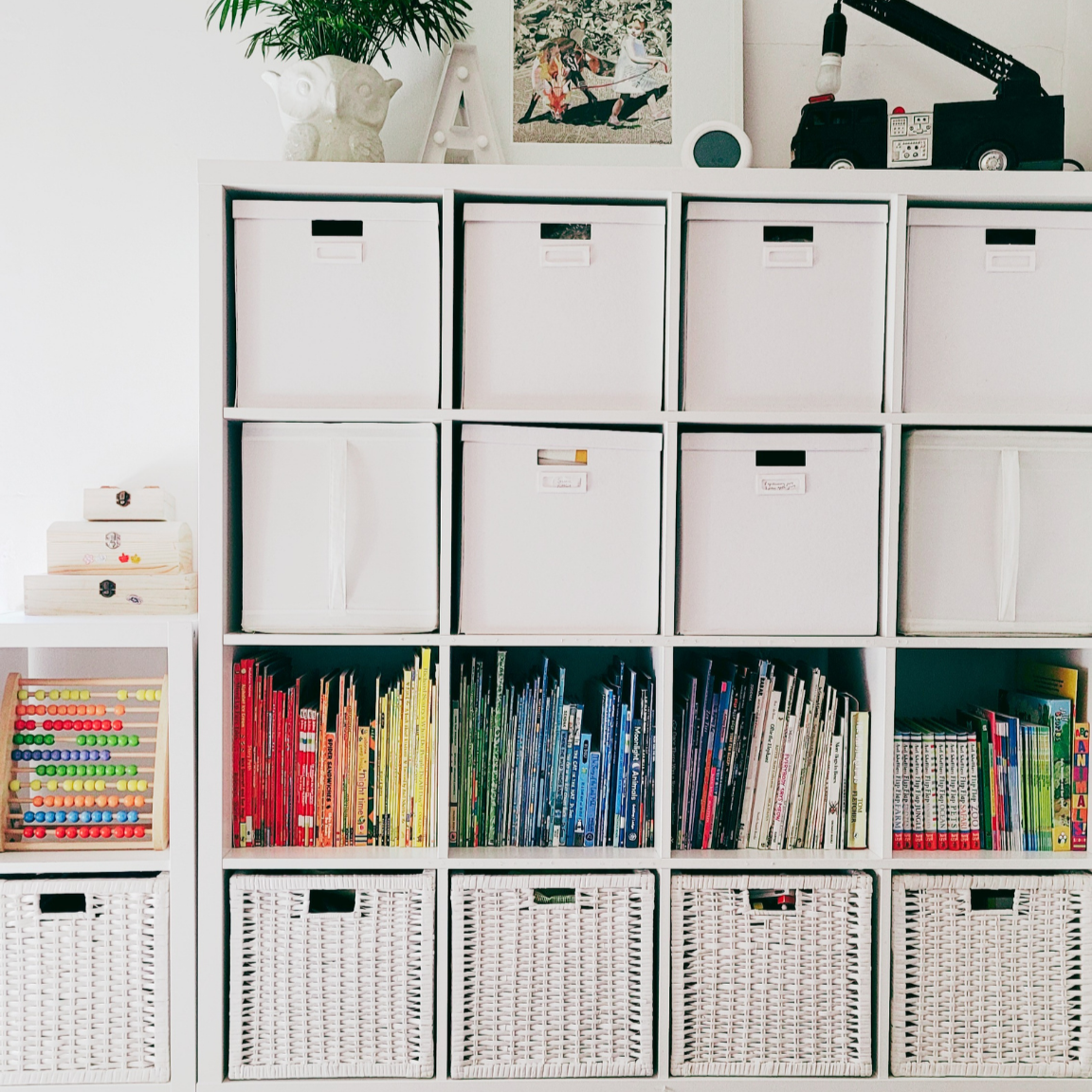 Organised children’s playroom with labelled storage boxes, colour-sorted books and wicker baskets.
