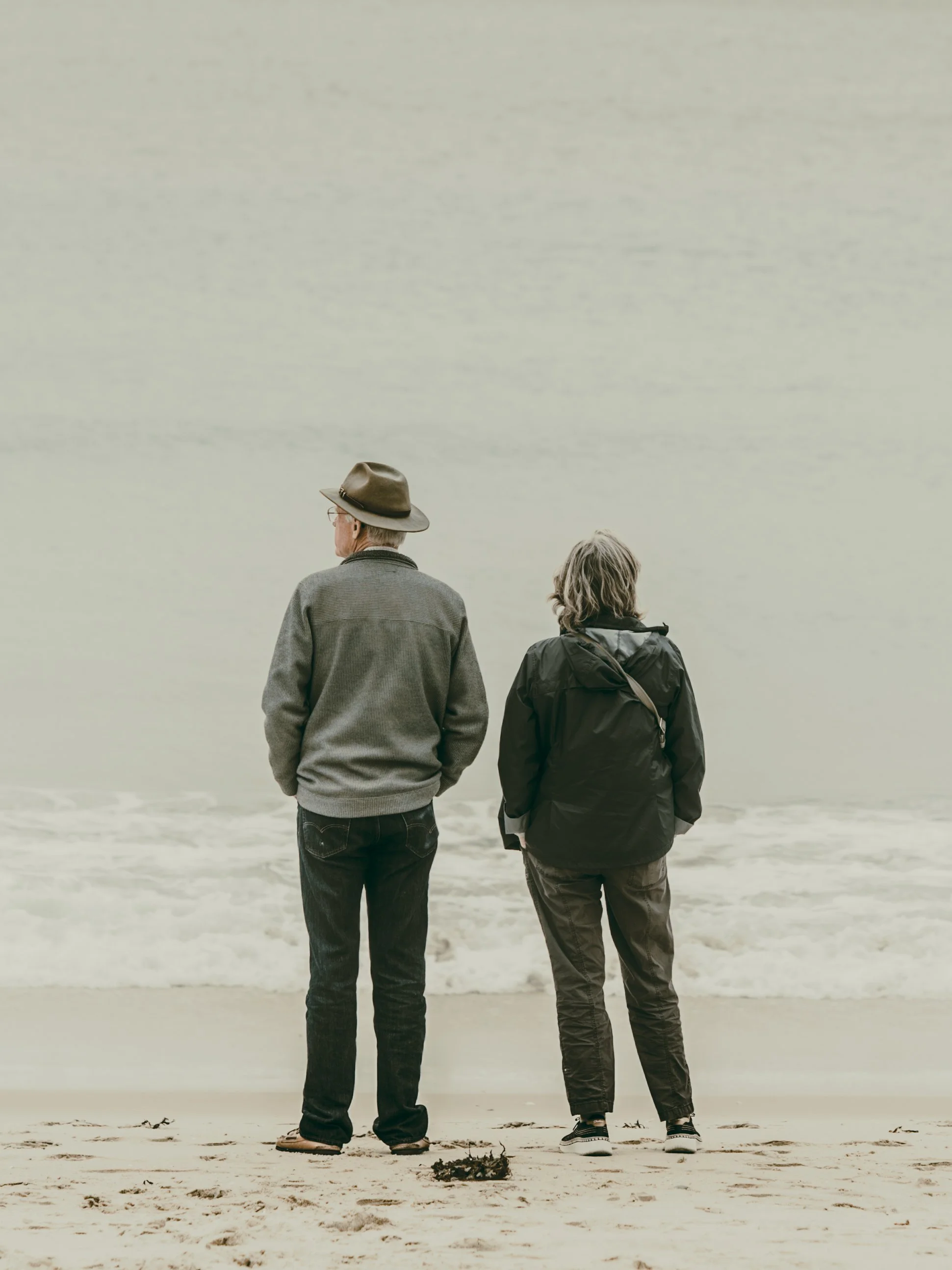 Man and woman side by side on a beach looking out to sea