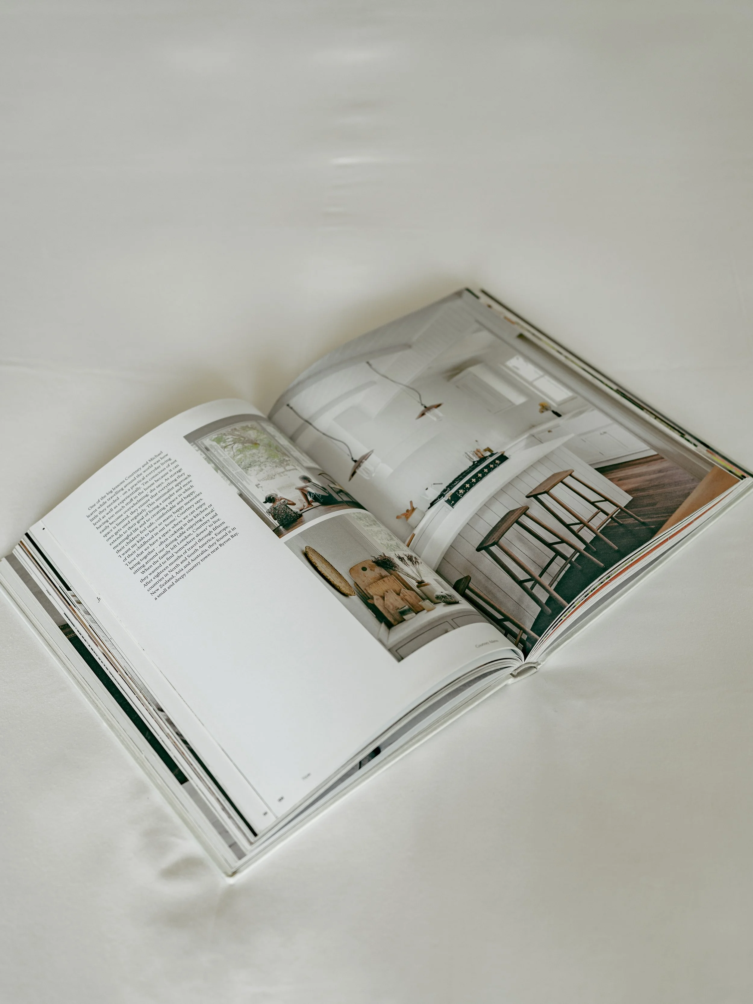 Open magazine showing interior design pictures and text on a white surface