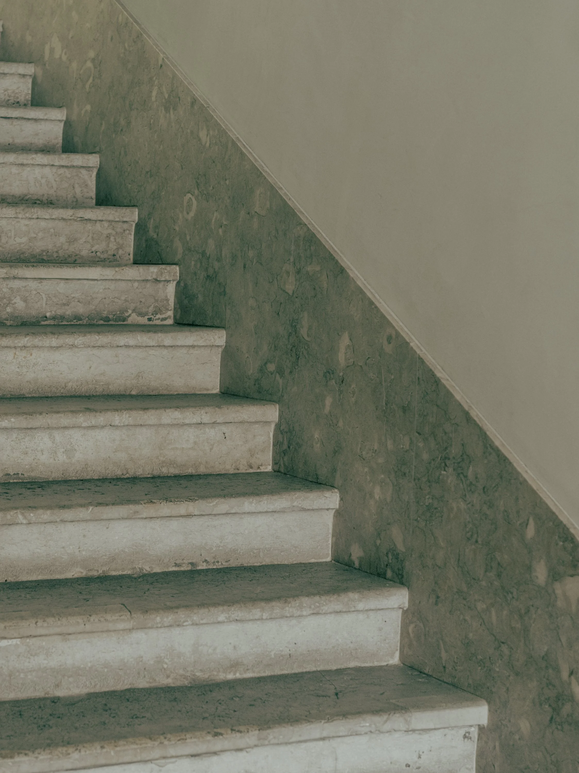 Concrete stairs with visible wear and a textured wall beside them.