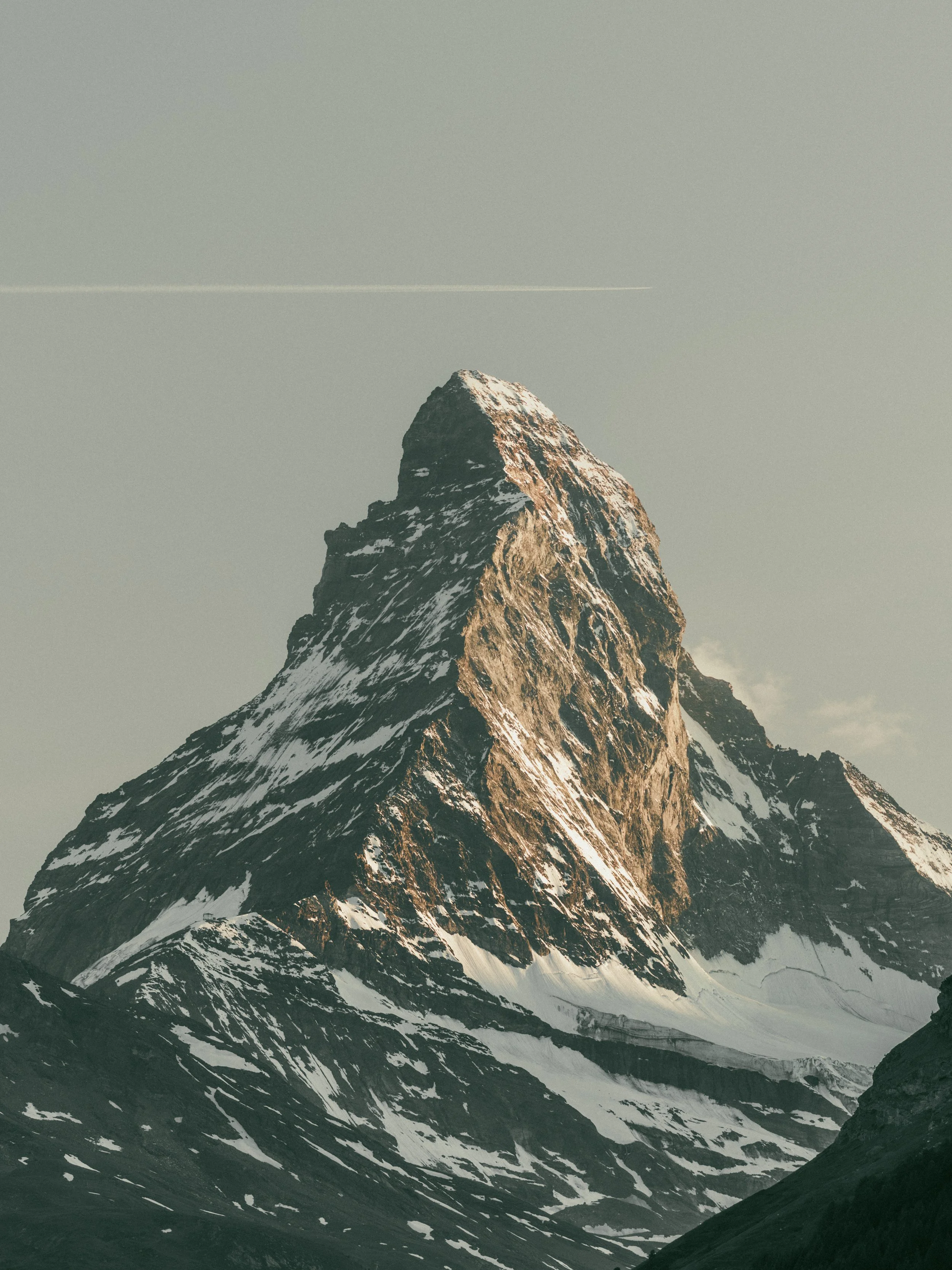 Snow-capped mountain peak with rugged slopes and surrounding valleys.