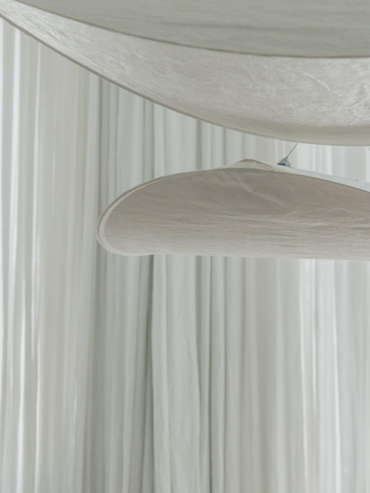 Close-up of white fabric or paper rolls hanging vertically with a curved shape, in a modern setting.
