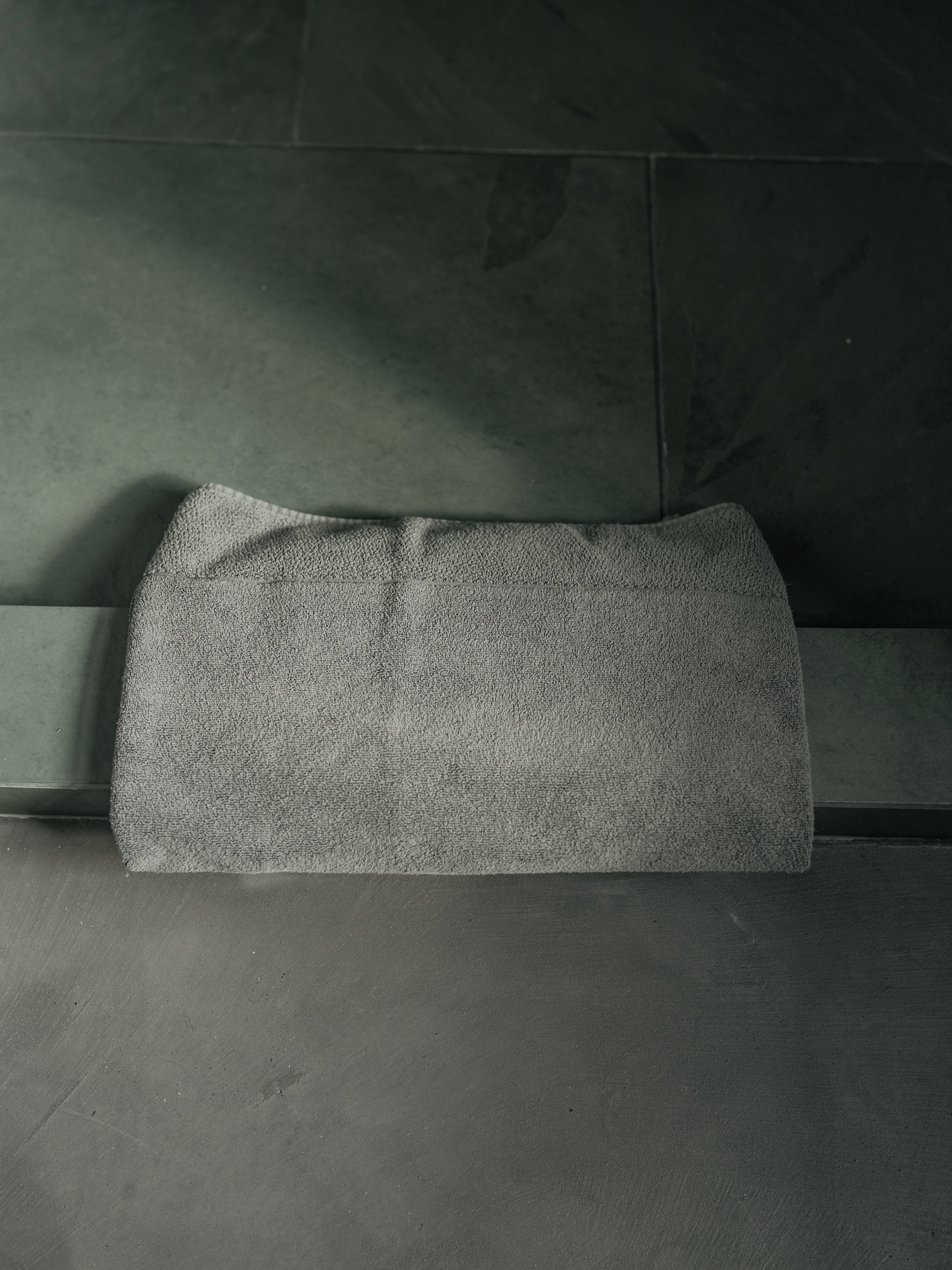Gray folded towel on dark gray tiled floor.
