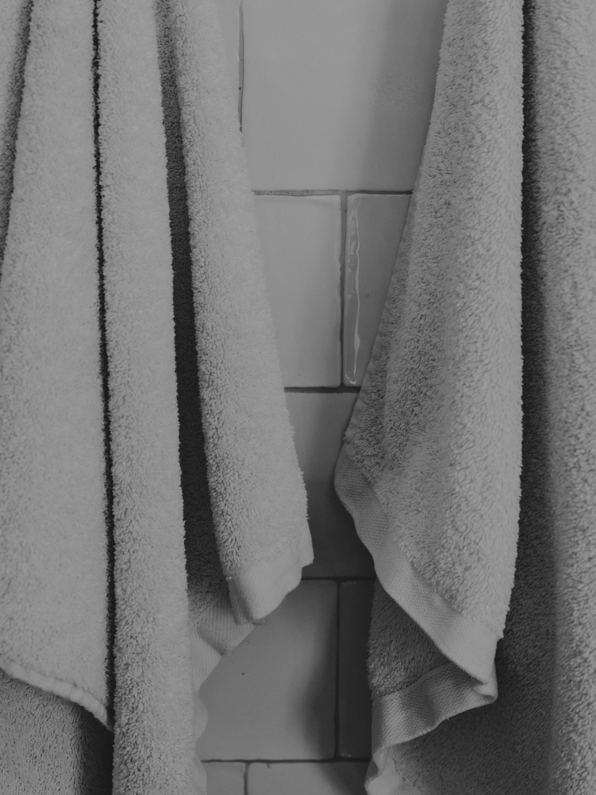 Stacked white towels on a tiled bathroom surface.