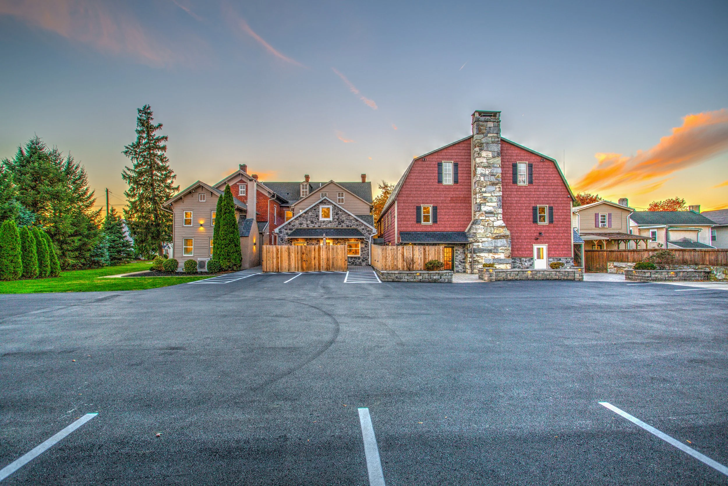 parking lot with 17 spaces with marked spaces in front of a row of residential houses during sunset.