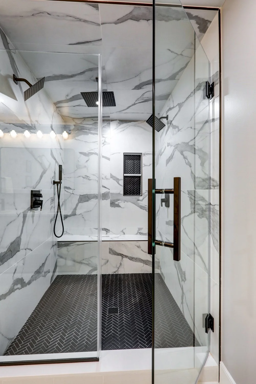 Large walk-in shower with multiple shower heads in primary bathroom on the first floor of The Barn