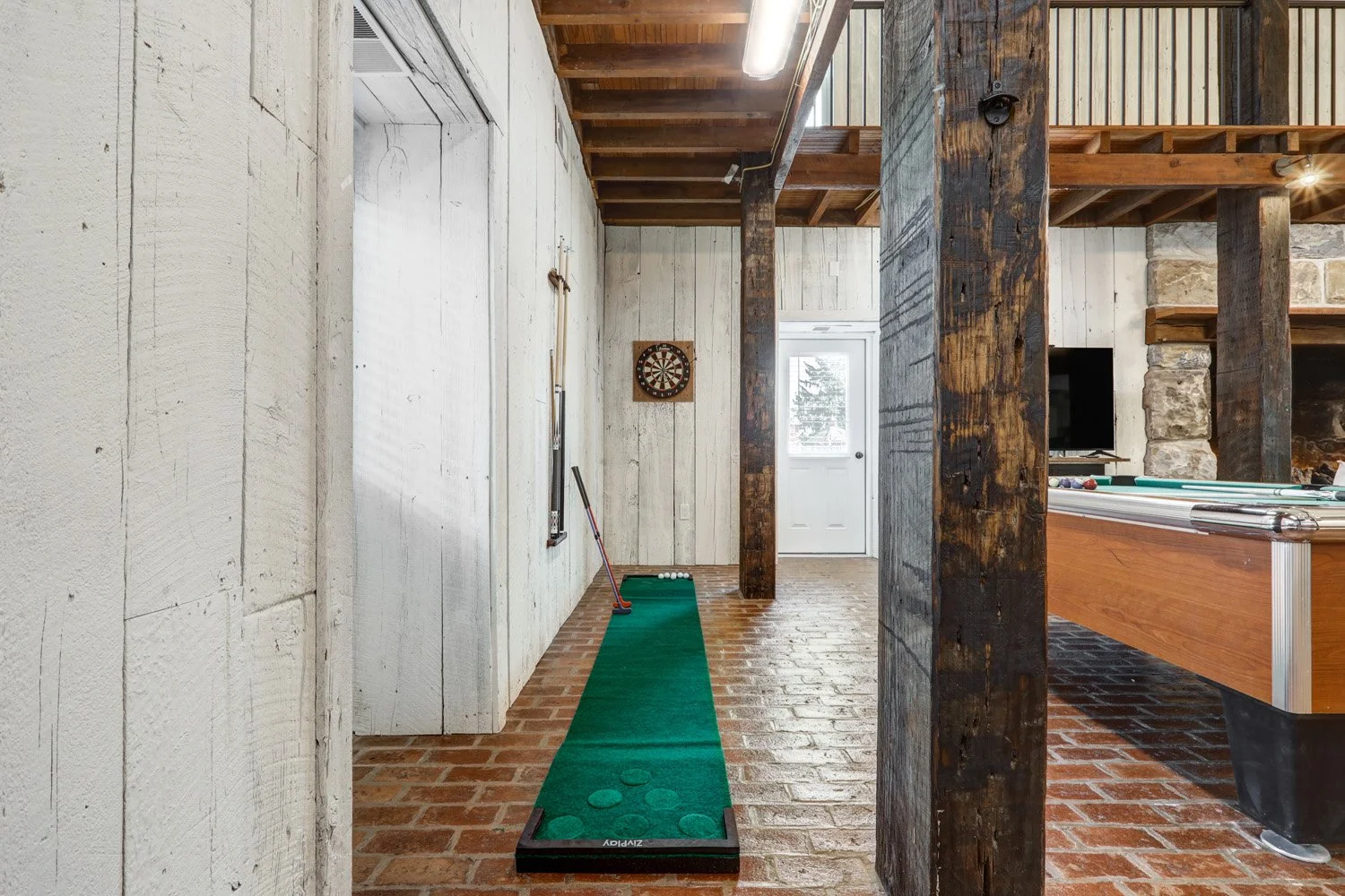 Game room area with pool table, foosball table, dart board, putterball game, Infinity game table, and record player. 
