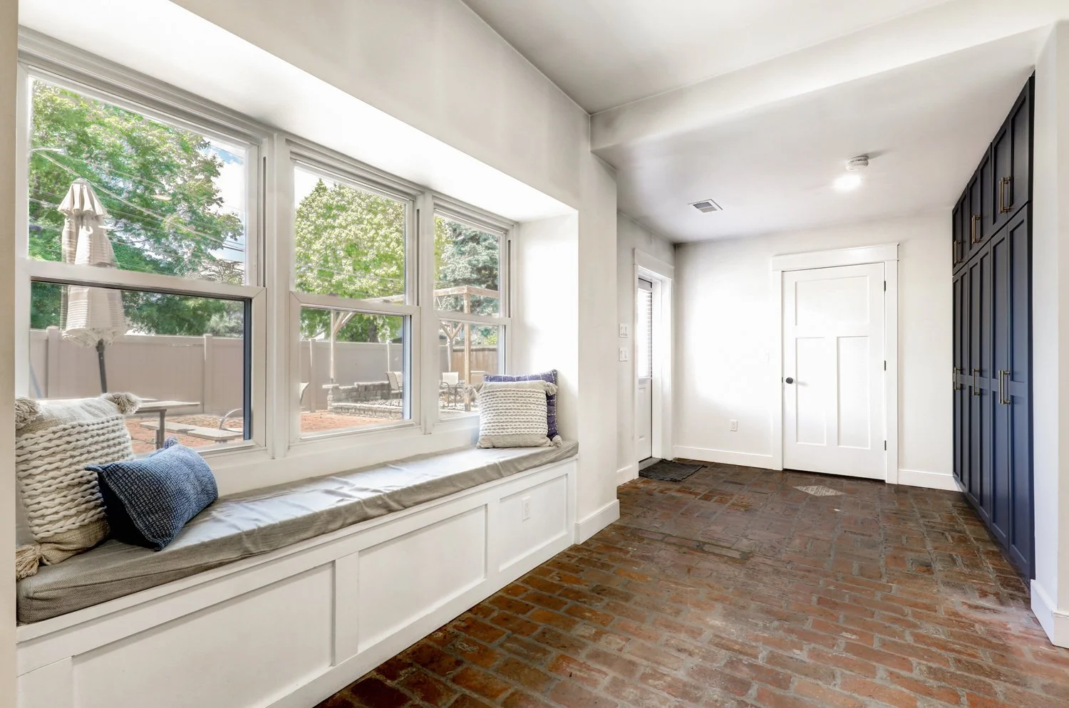 Window seat off of kitchen looking towards the brick courtyard with fireplace, wood pellet smoker/grill, charcoal grill, and outdoor dining table. Firewood, charcoal, wood pellets, and grilling supplies are provided. 