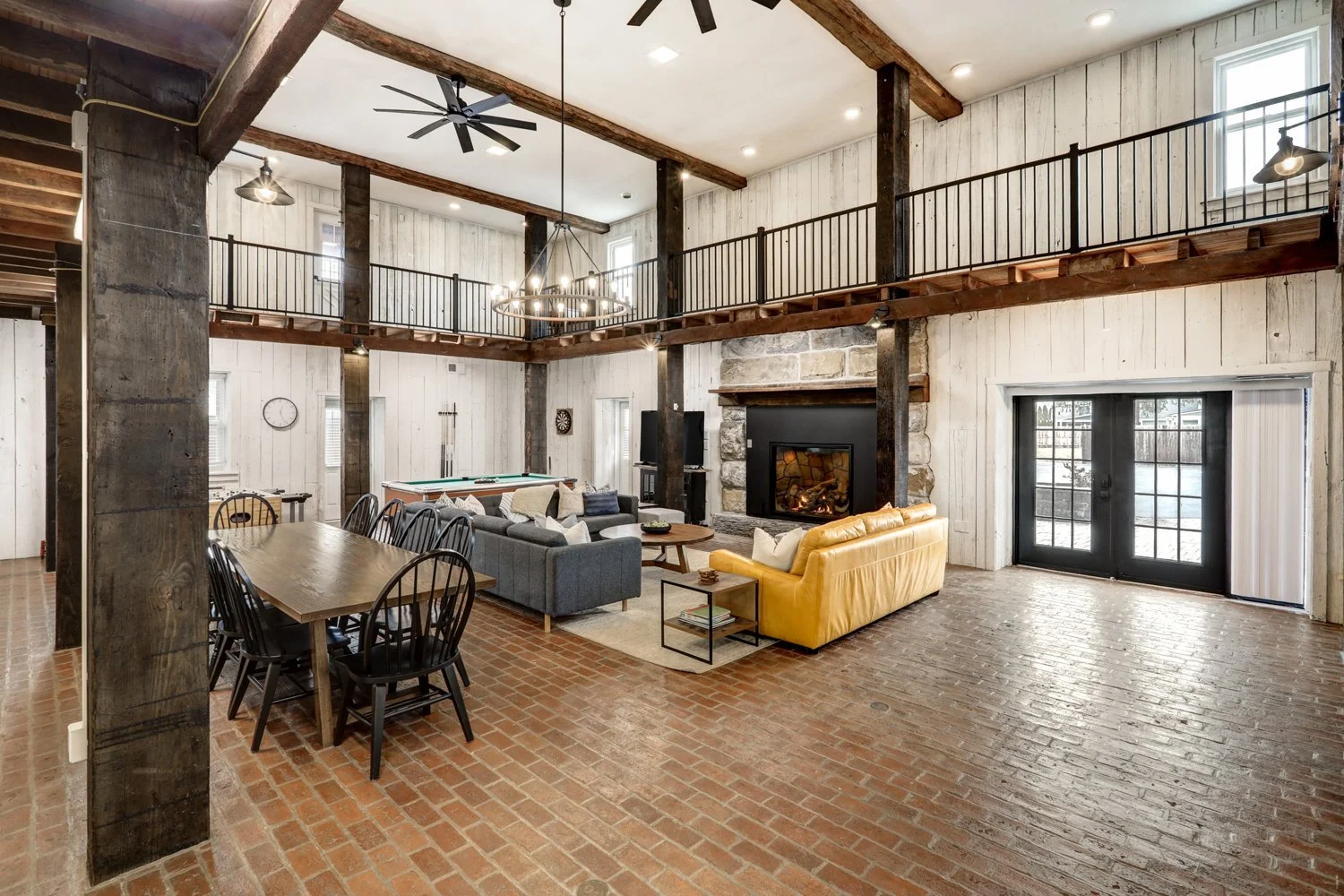 First floor of The Barn with propane-fueled fireplace, game area, large dining table for 10, with open floor plan to kitchen on the left