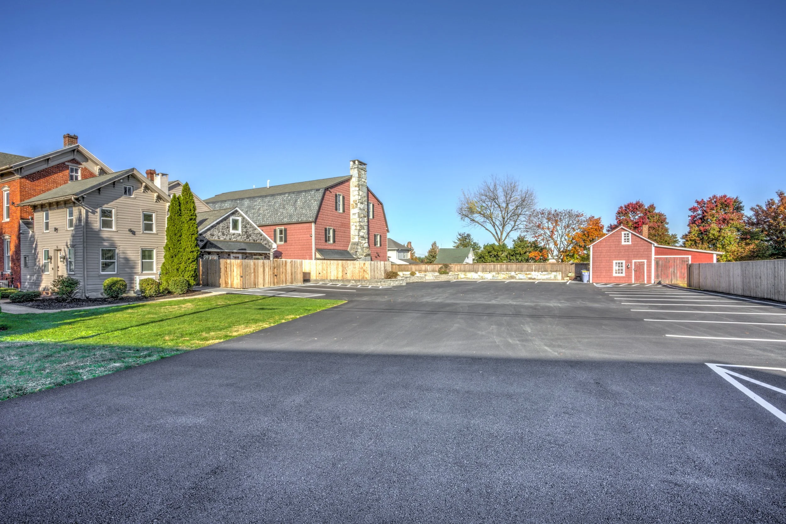 parking lot with 17 marked spaces, surrounded by residential houses with trees and a clear blue sky.
