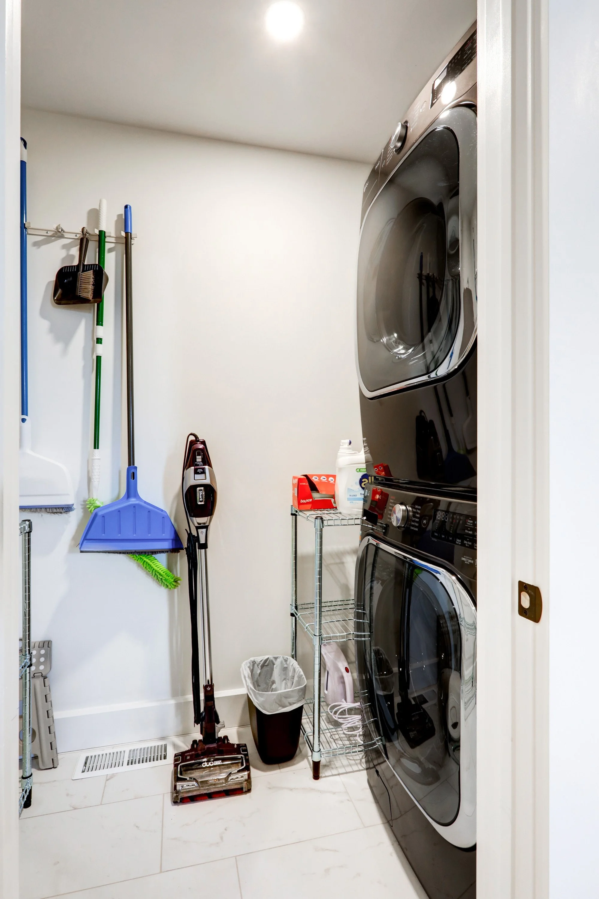 A laundry room with cleaning supplies, vacuum, and a washer and dryer.