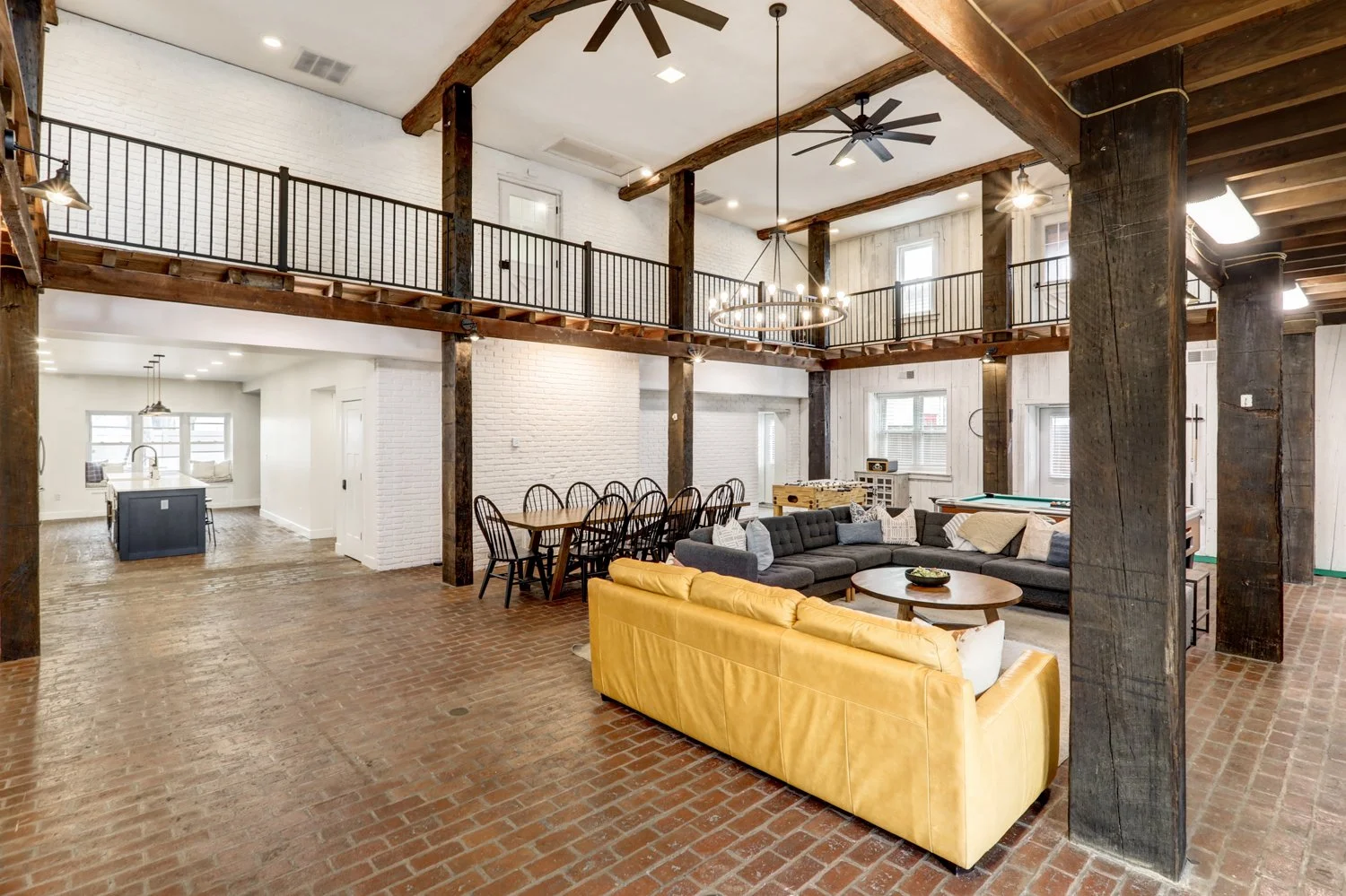First floor of The Barn with propane-fueled fireplace, game area, large dining table for 10, with open floor plan to kitchen on the left