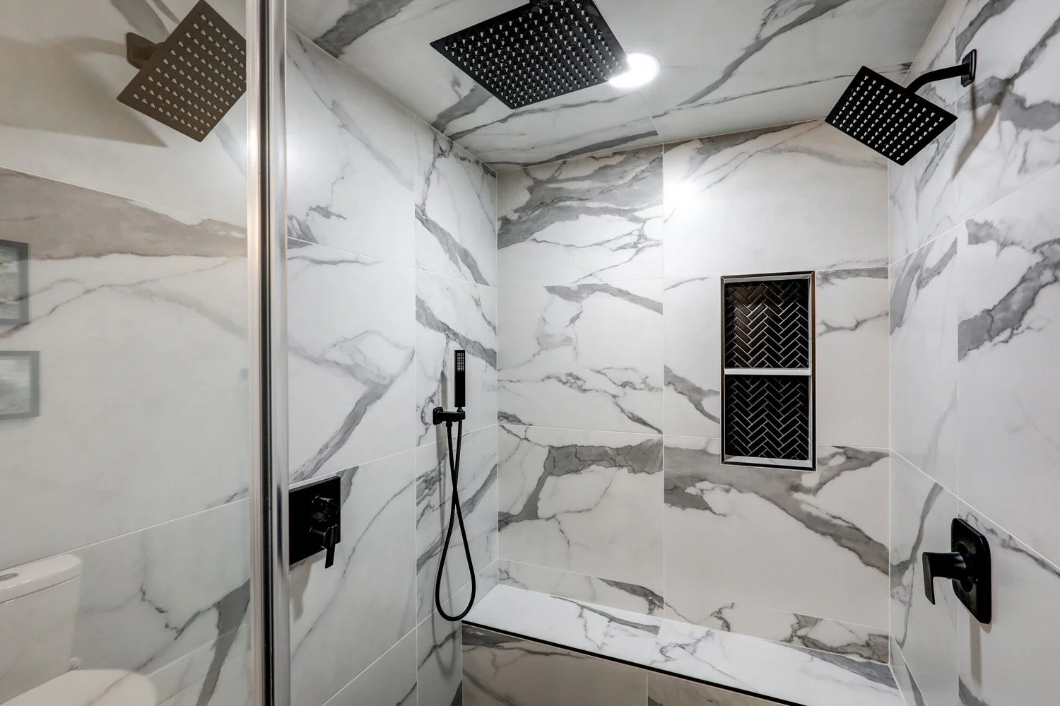 Large walk-in shower with multiple shower heads in primary bathroom on the first floor of The Barn
