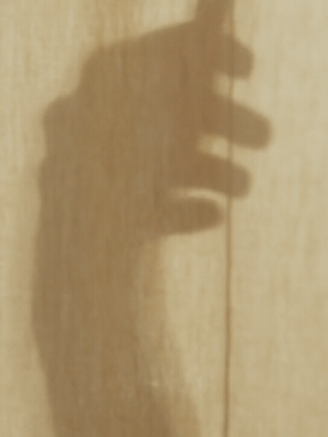 Close-up of a hand gripping a vertical pole or rod, with a plain background.