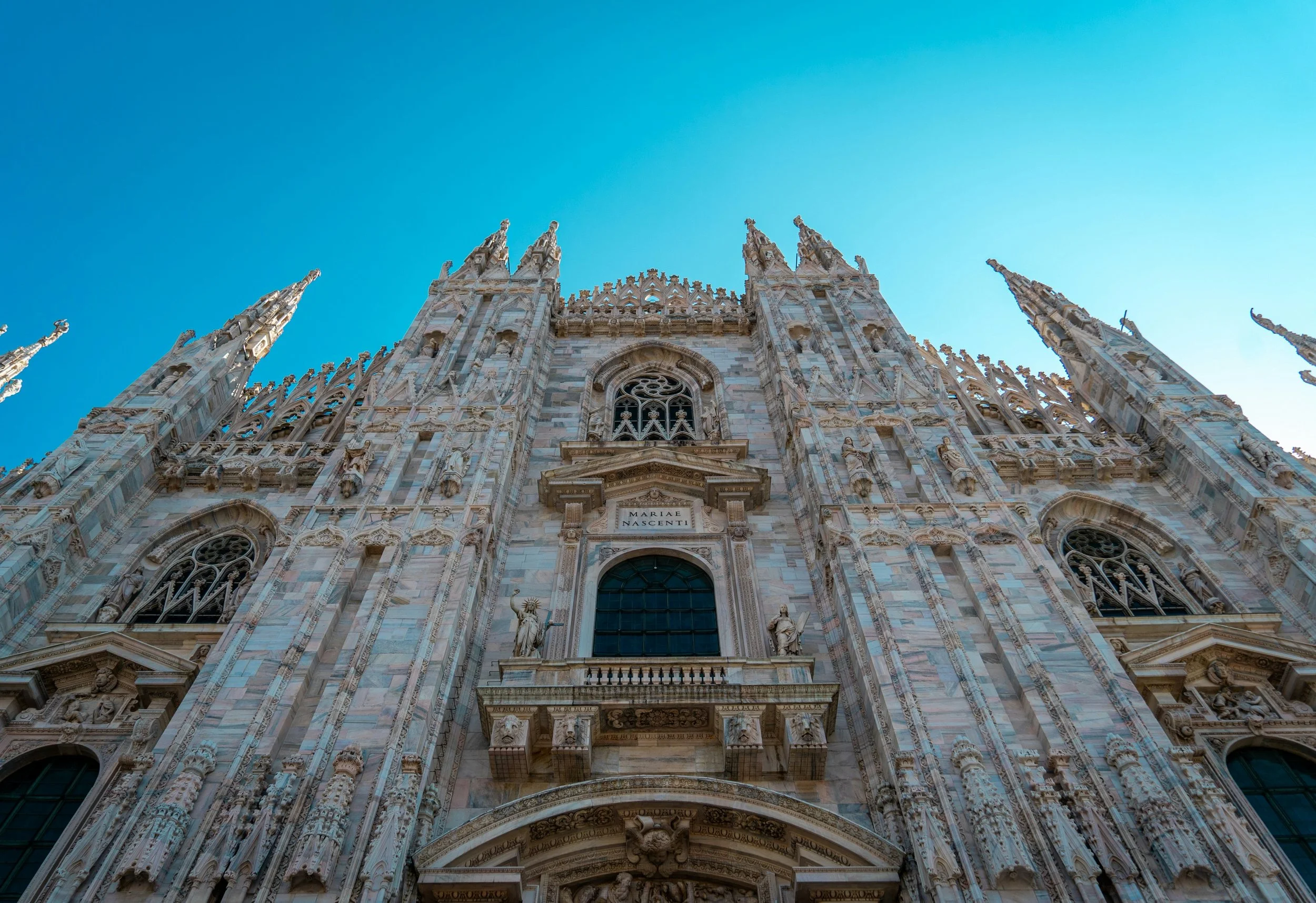 Facade of a Gothic cathedral with intricate carvings and statues, under a clear blue sky.