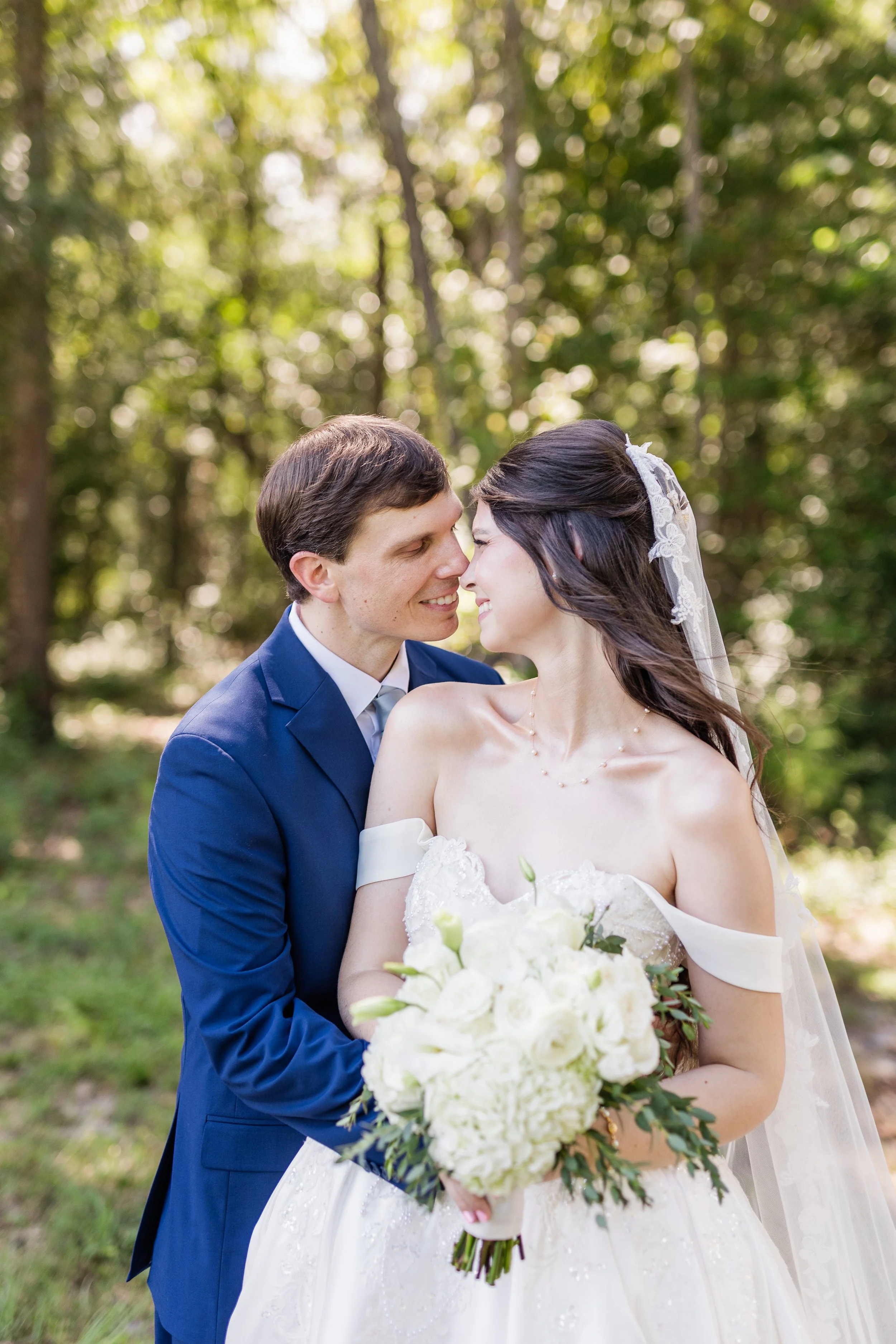 Newlyweds with foreheads touching in a forest, bridal hair and makeup by Briar & Bleu