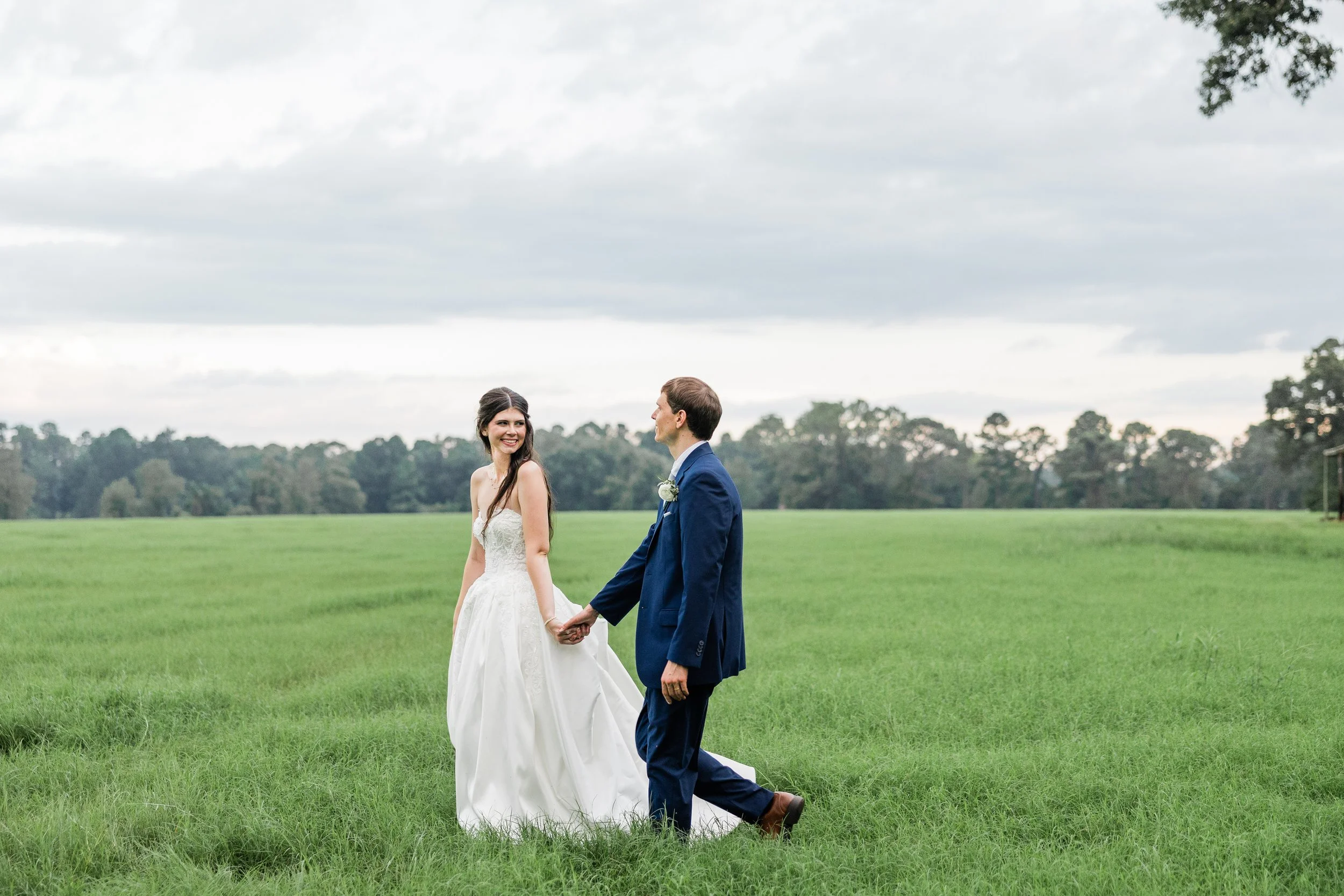 Smiling bride walking hand in hand with groom, bridal hair and makeup by Briar & Bleu