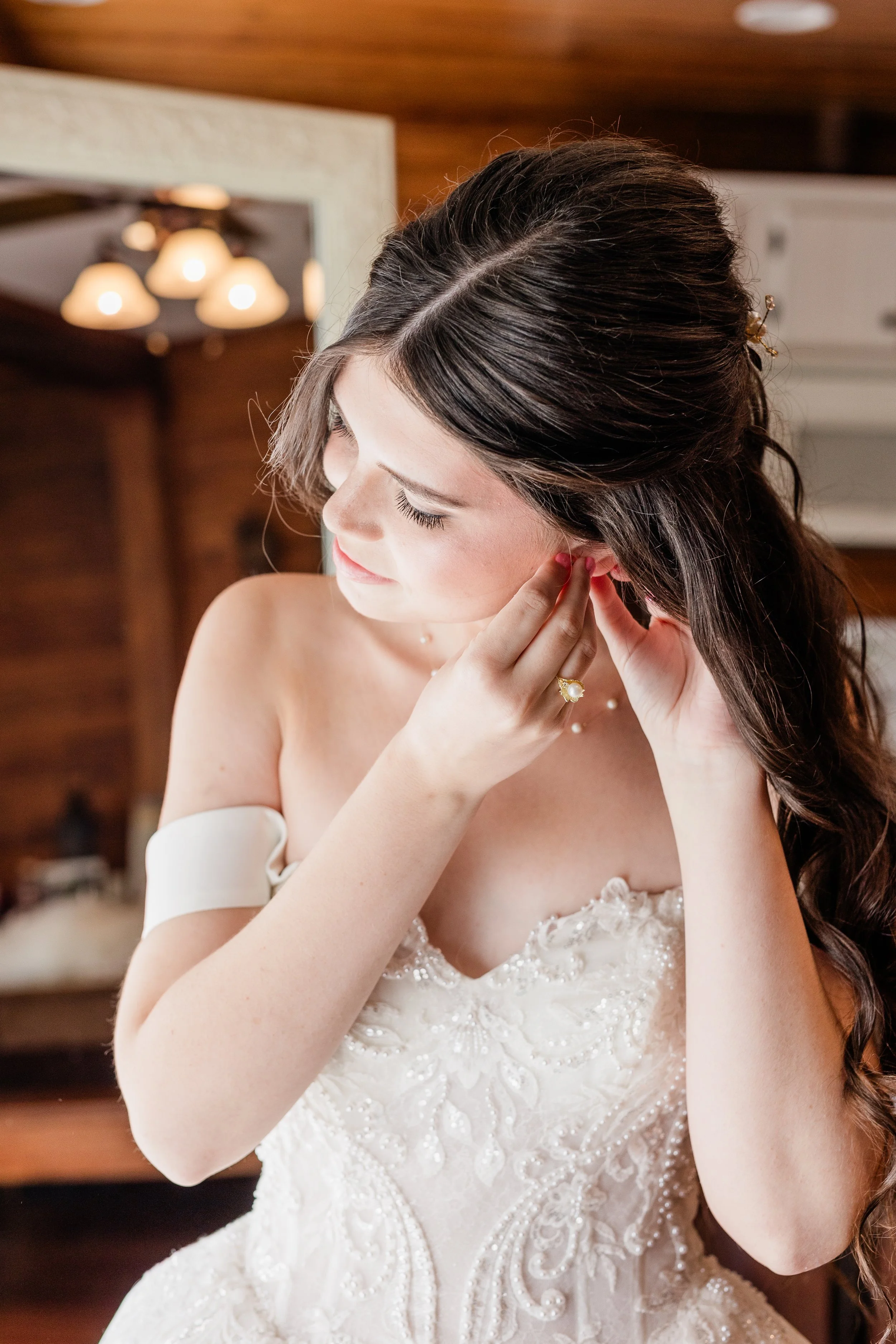 Bride adjusting earring, bridal hair and makeup by Briar & Bleu