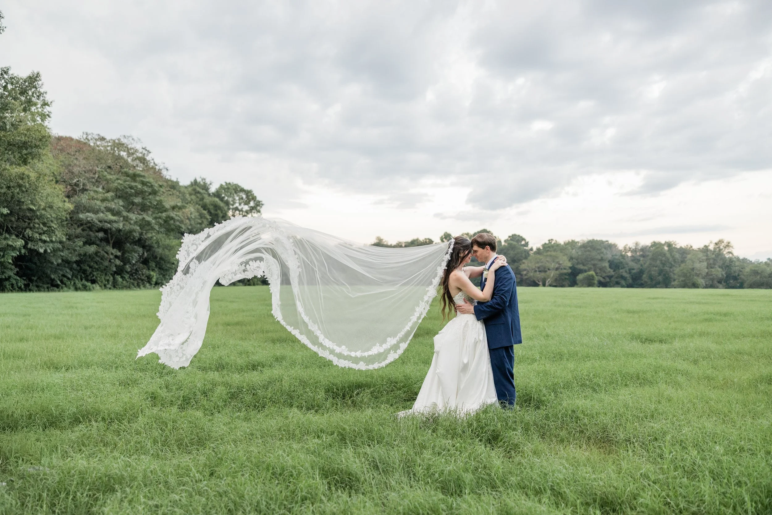 Bride and groom kissing in a field, bridal hair and makeup by Briar & Bleu